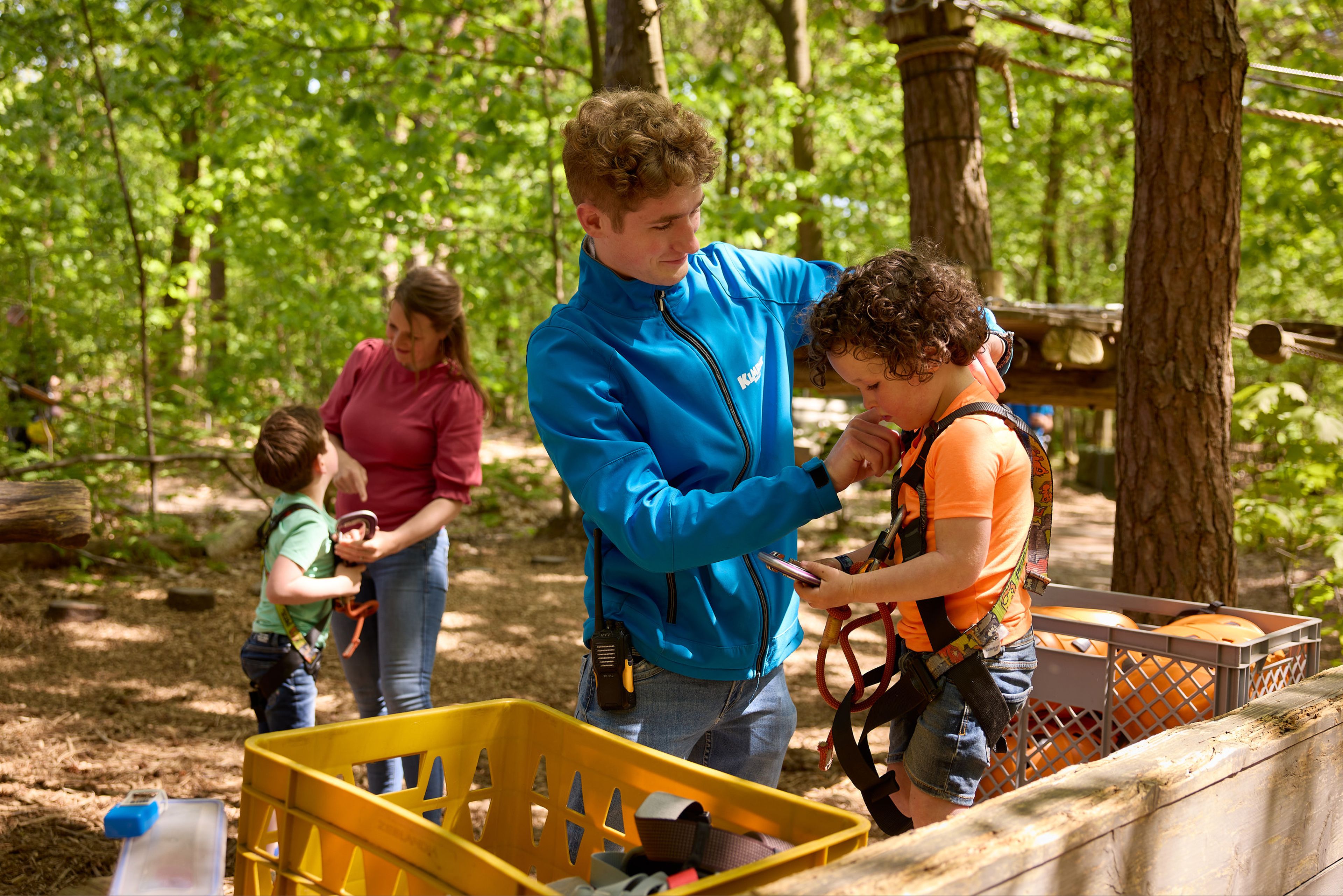 Medewerker helpt kind met klimtuig op het Pico Parcours bij Klimrijk Brabant