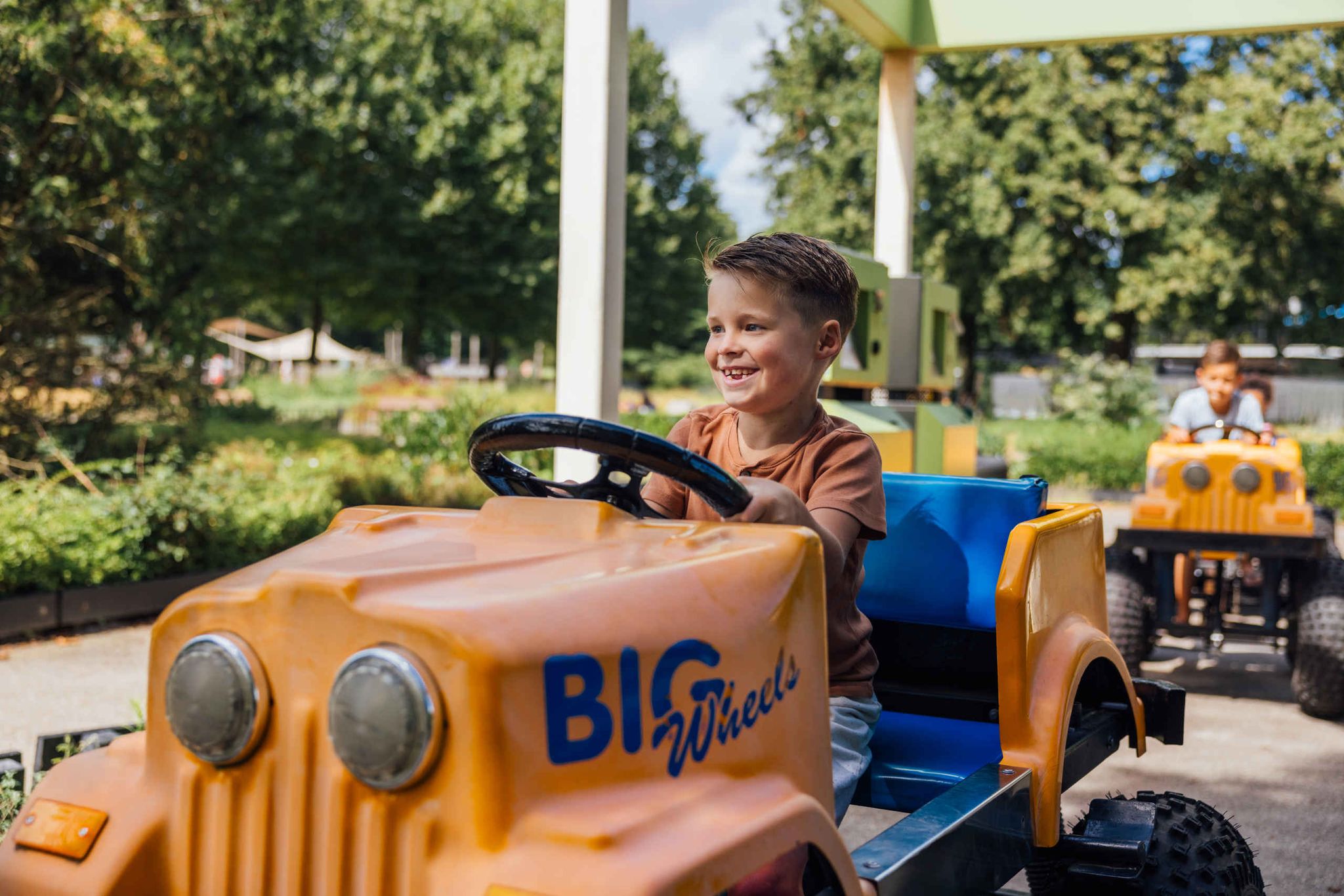 Kinderen in Bigwheels auto in Speelland Outdoor Beekse Bergen