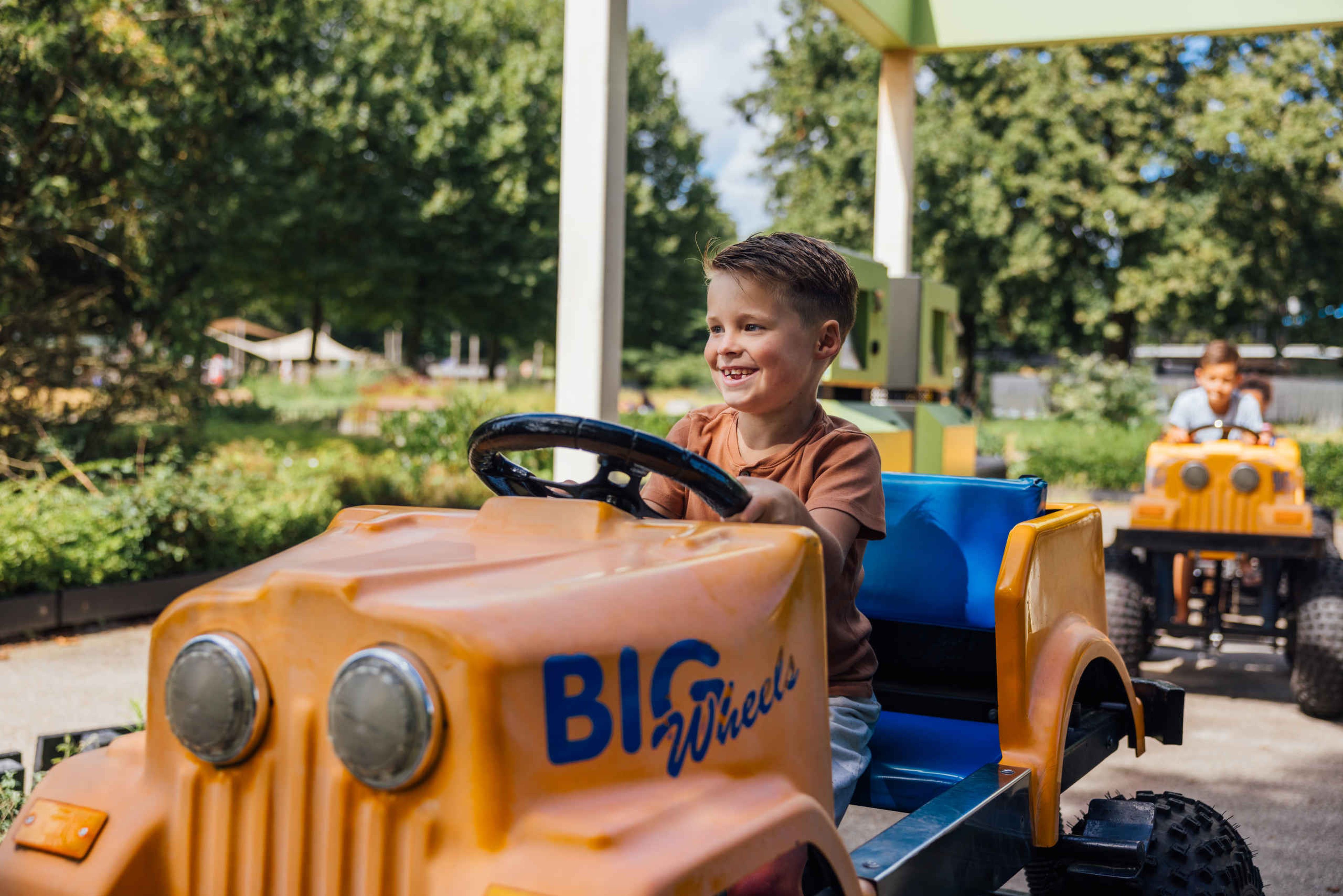 Kinderen in Bigwheels auto in Speelland Outdoor Beekse Bergen