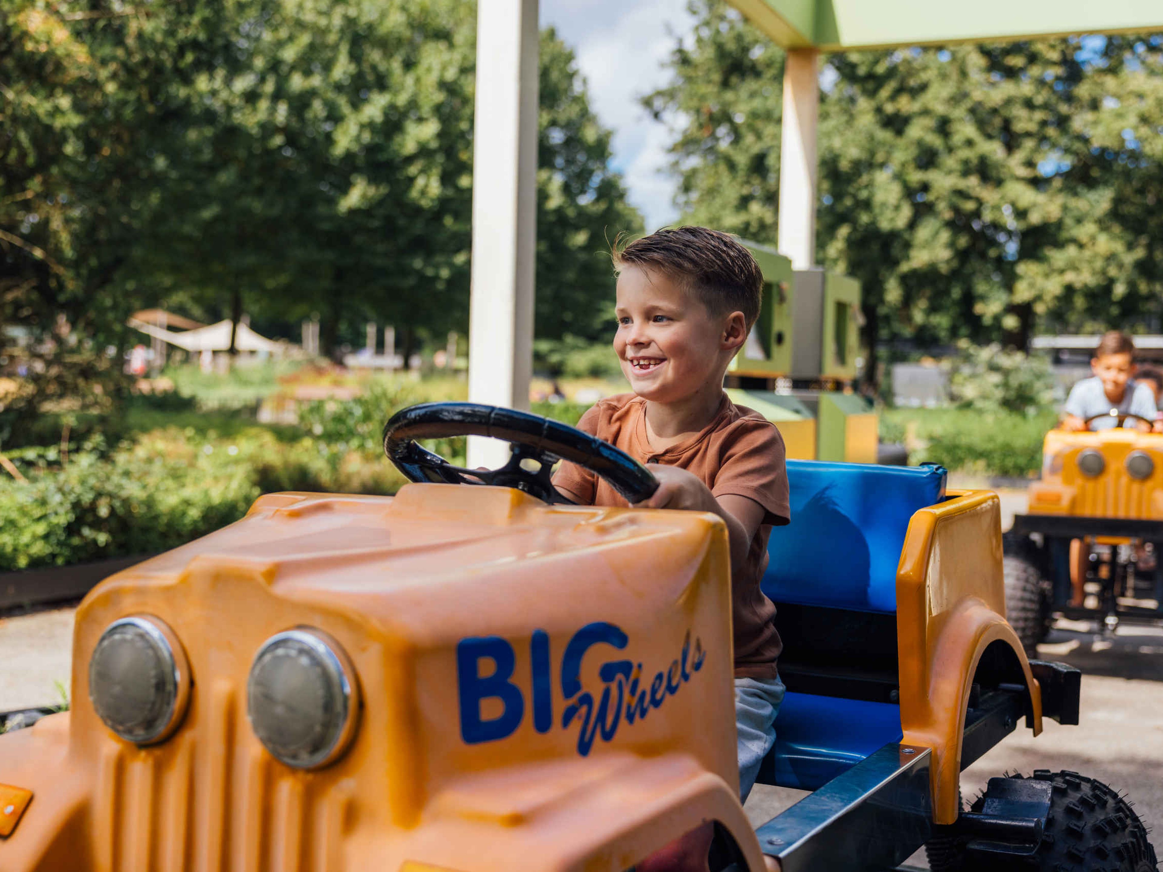 Kinderen in Bigwheels auto in Speelland Outdoor Beekse Bergen