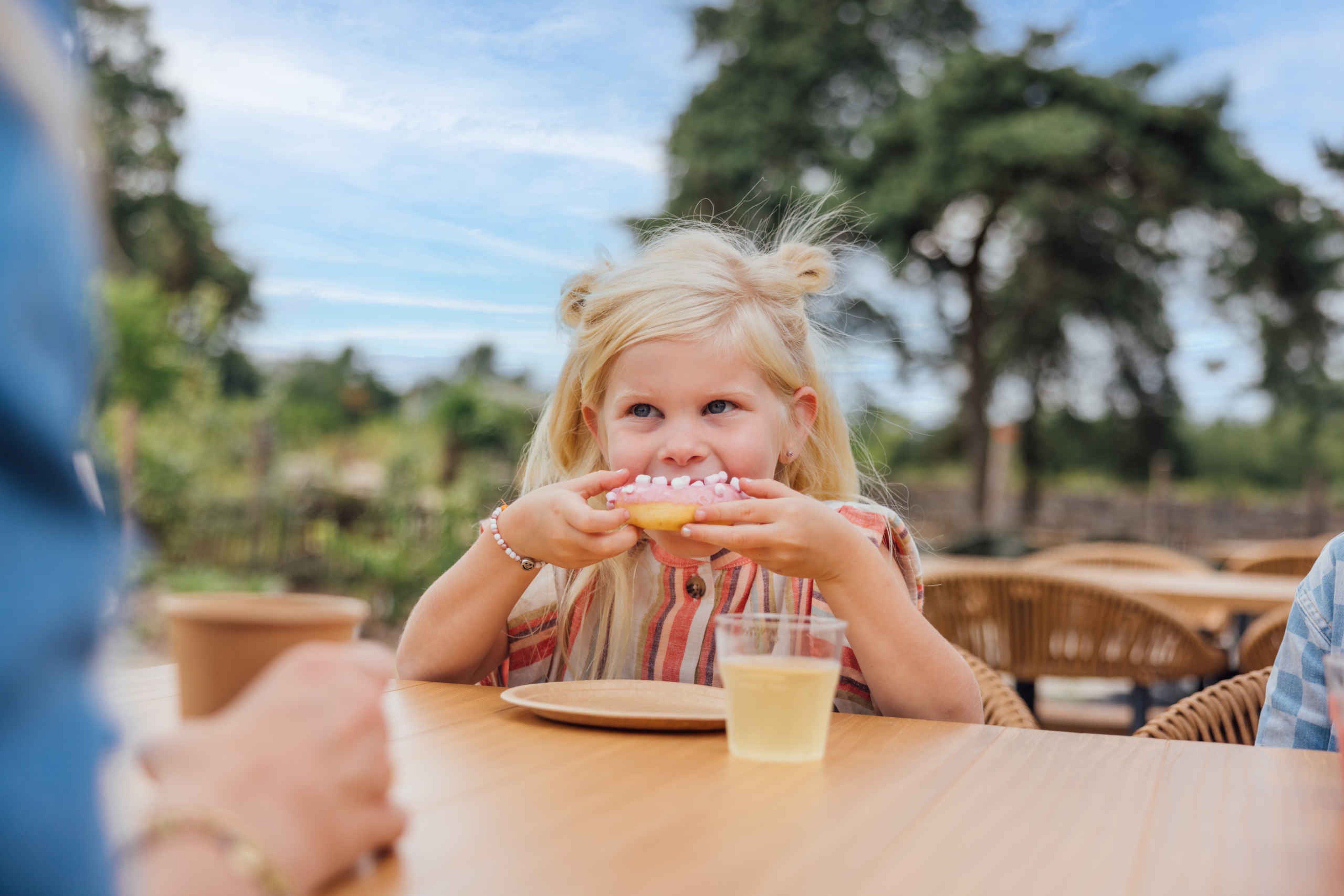 Meisje eet een donut op het terras van restaurant Mugunda in Safaripark Beekse Bergen