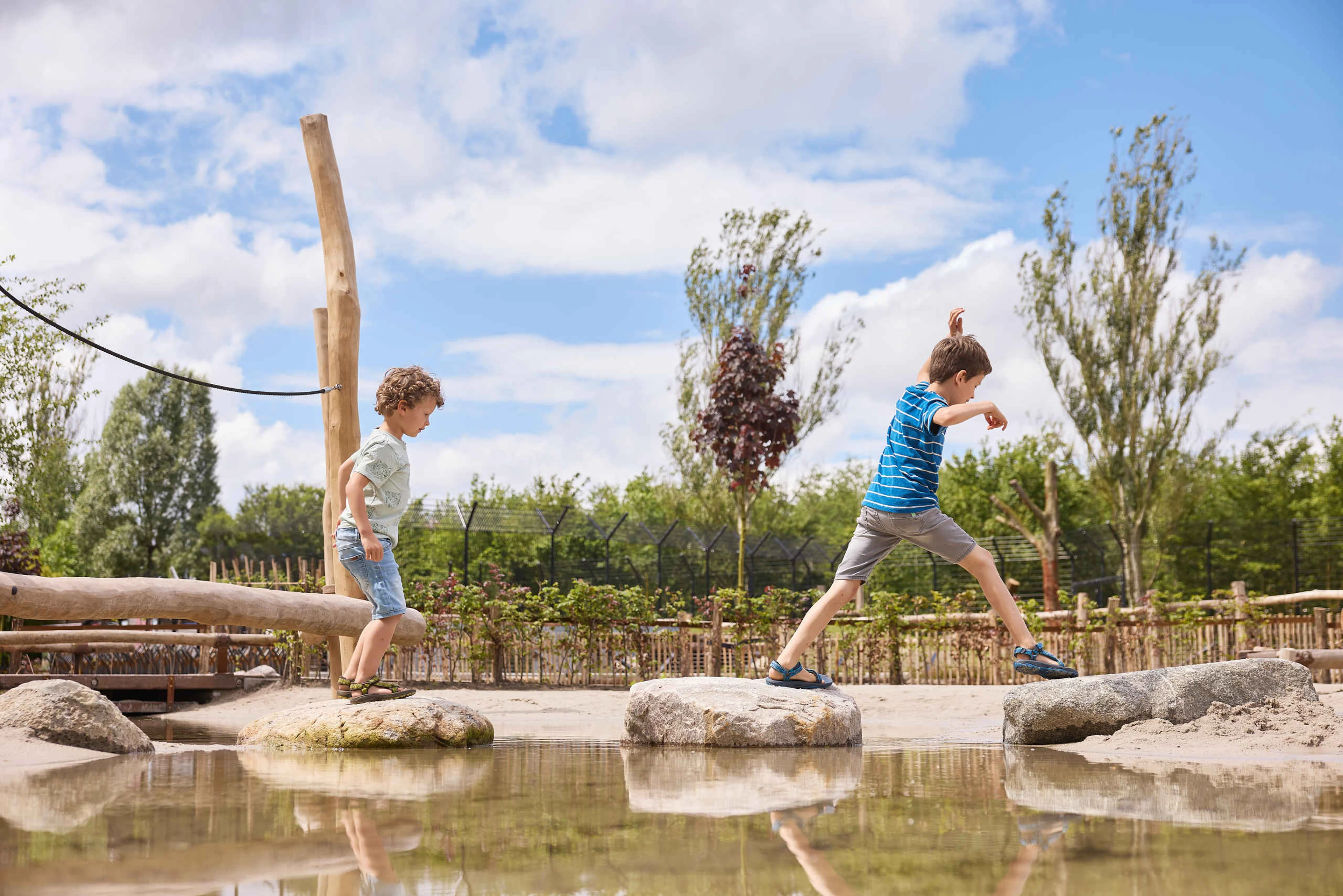 Twee jongens lopen over de stenen in het water bij de waterspeeltuin bij Eindhoven Zoo.