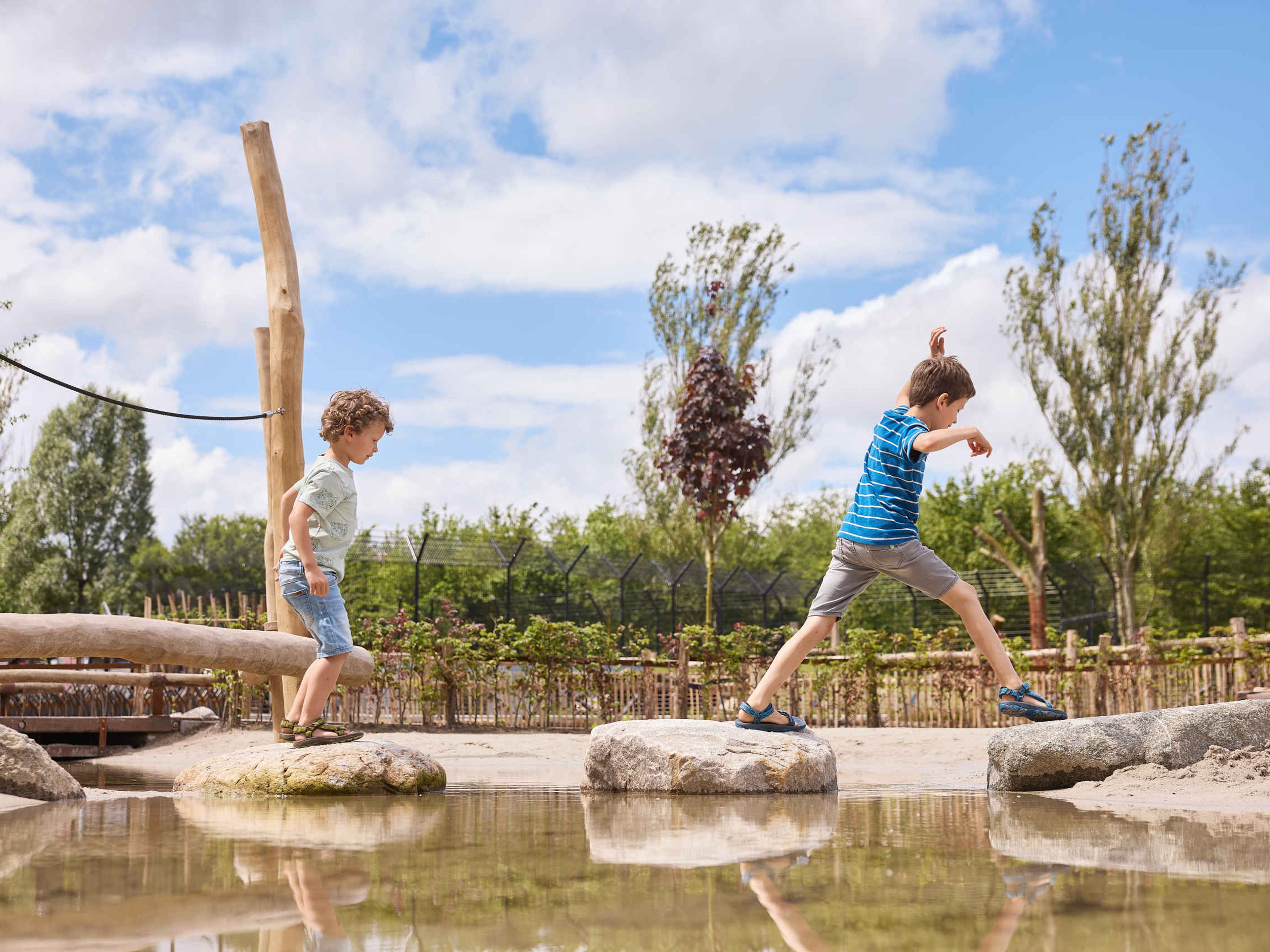Twee jongens lopen over de stenen in het water bij de waterspeeltuin bij Eindhoven Zoo.