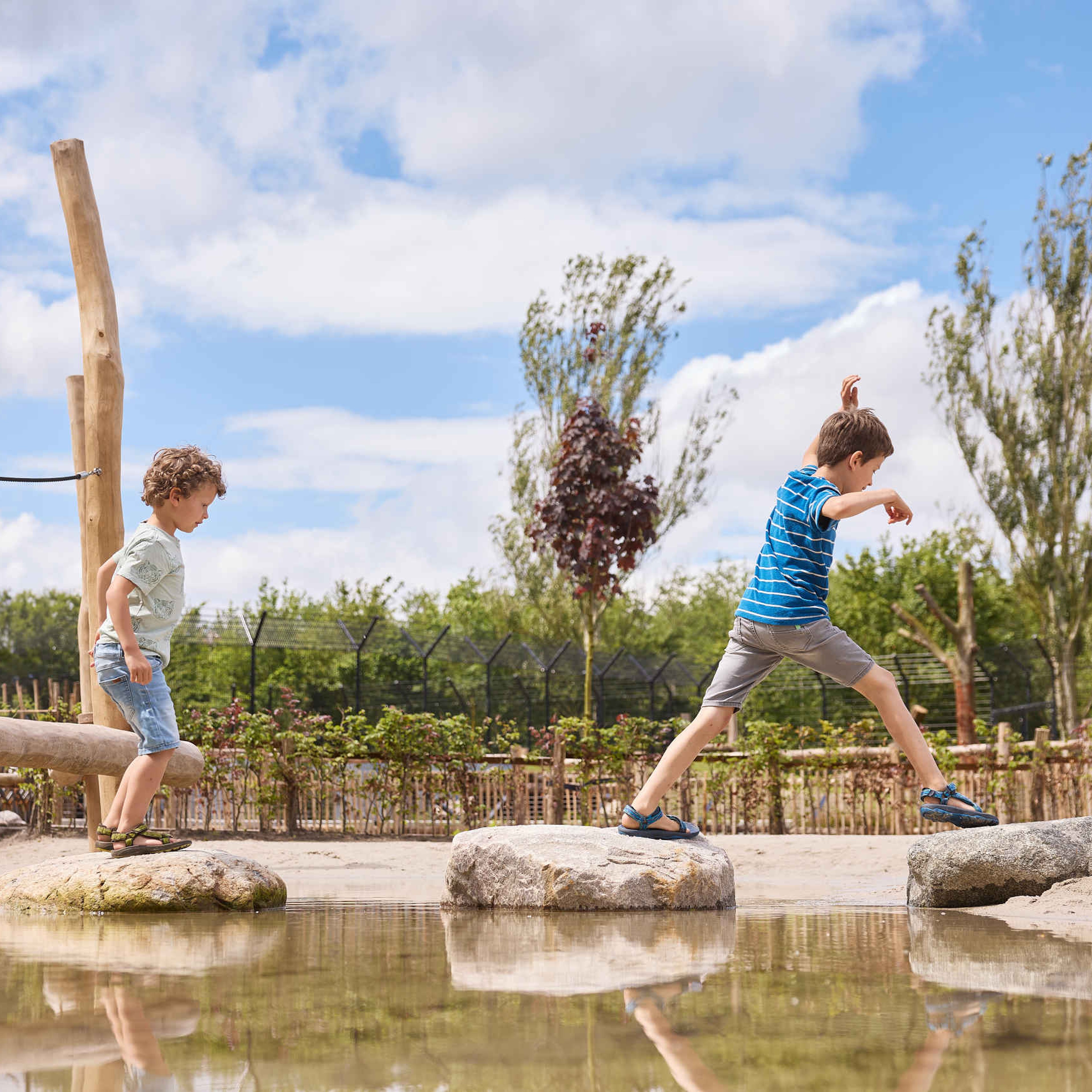 Twee jongens lopen over de stenen in het water bij de waterspeeltuin bij Eindhoven Zoo.
