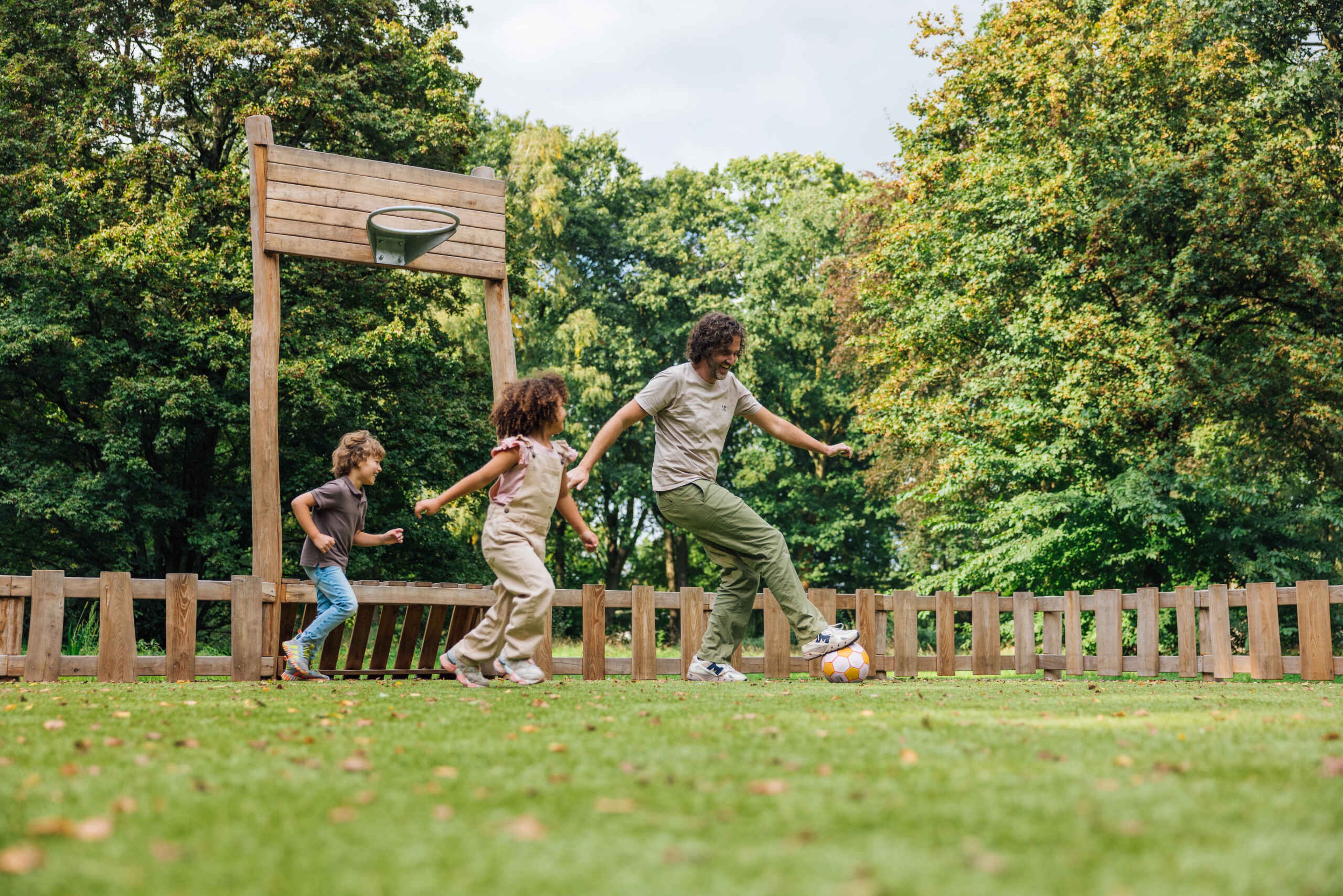 Vader met kinderen aan het voetballen in de pannakooi in Vakantie Dierenbos