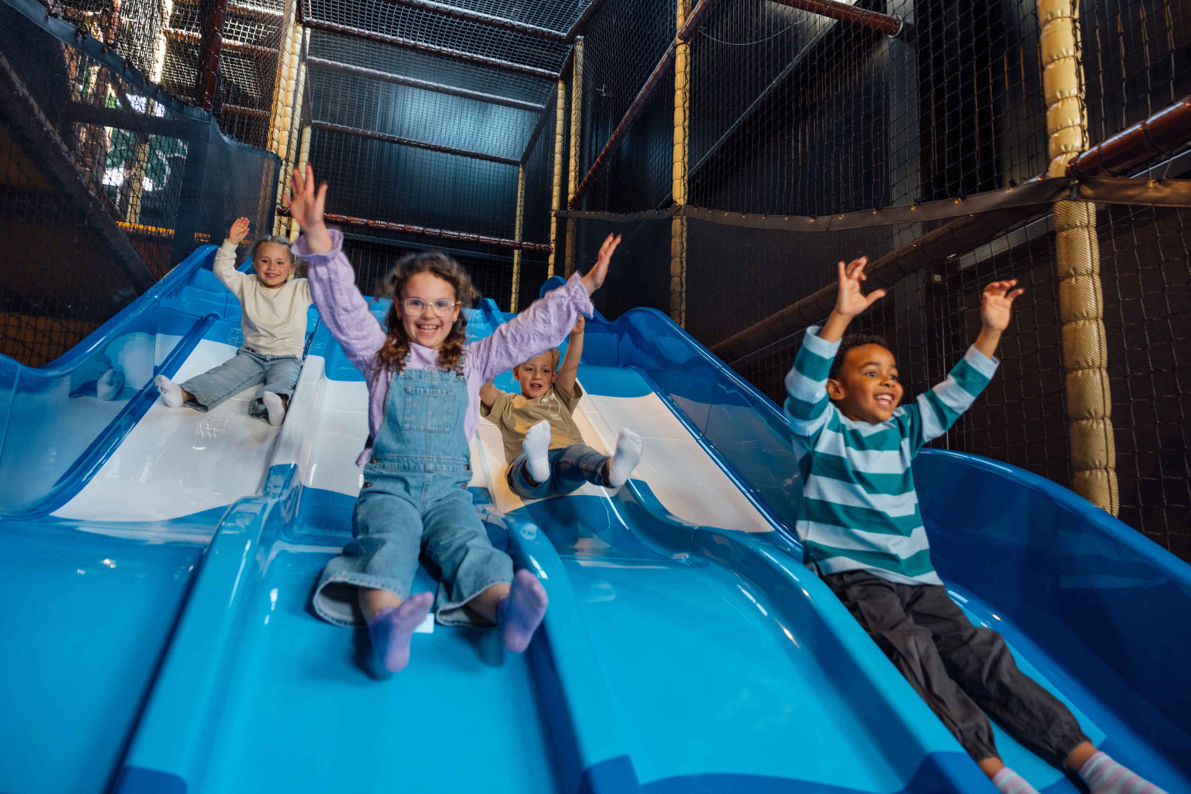 Vier kinderen op de grote glijbaan bij Speelland Indoor
