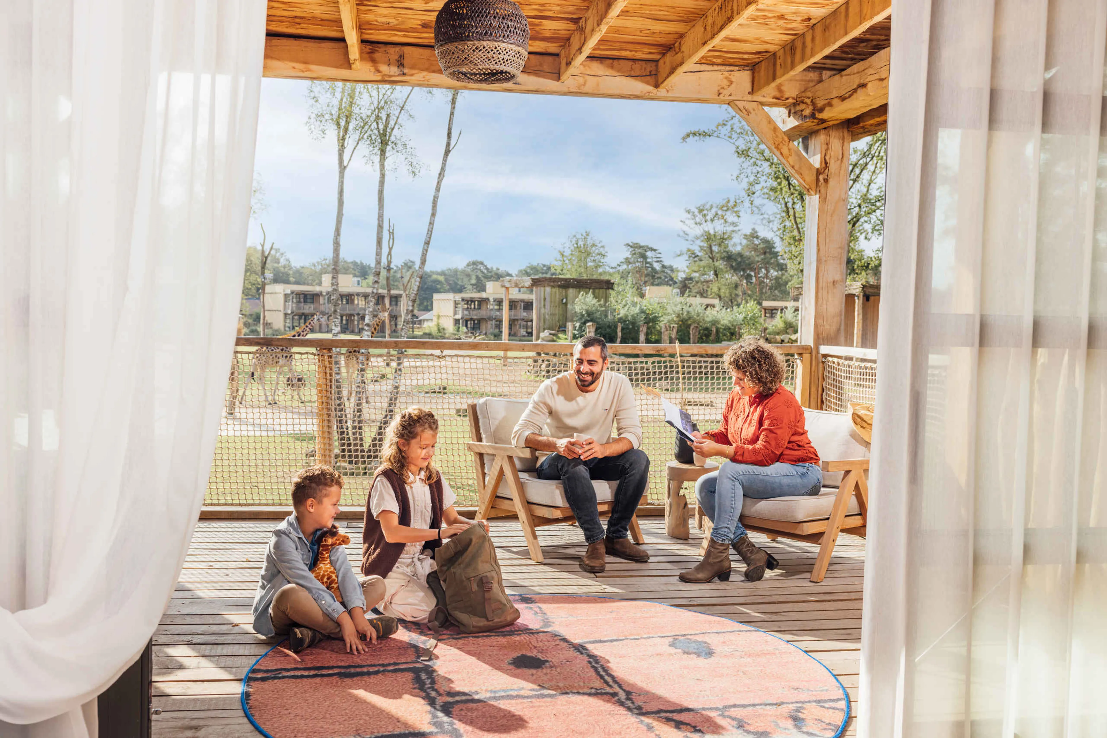 Een gezin zit op het balkon van hun Savanne Room bij Safari Hotel Beekse Bergen.