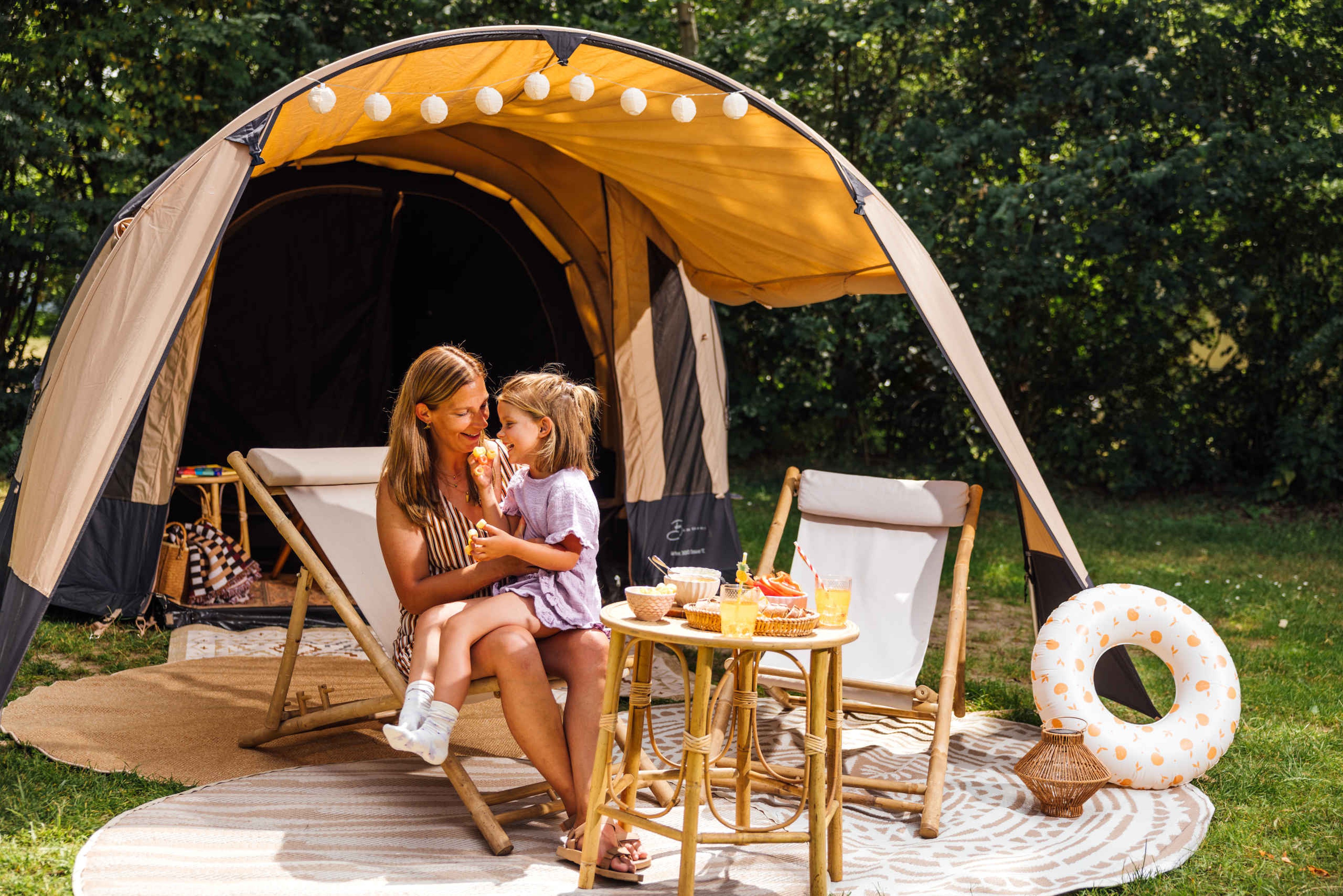 Een vrouw en haar dochter zitten bij een tent op de camping van Lake Resort Beekse Bergen.