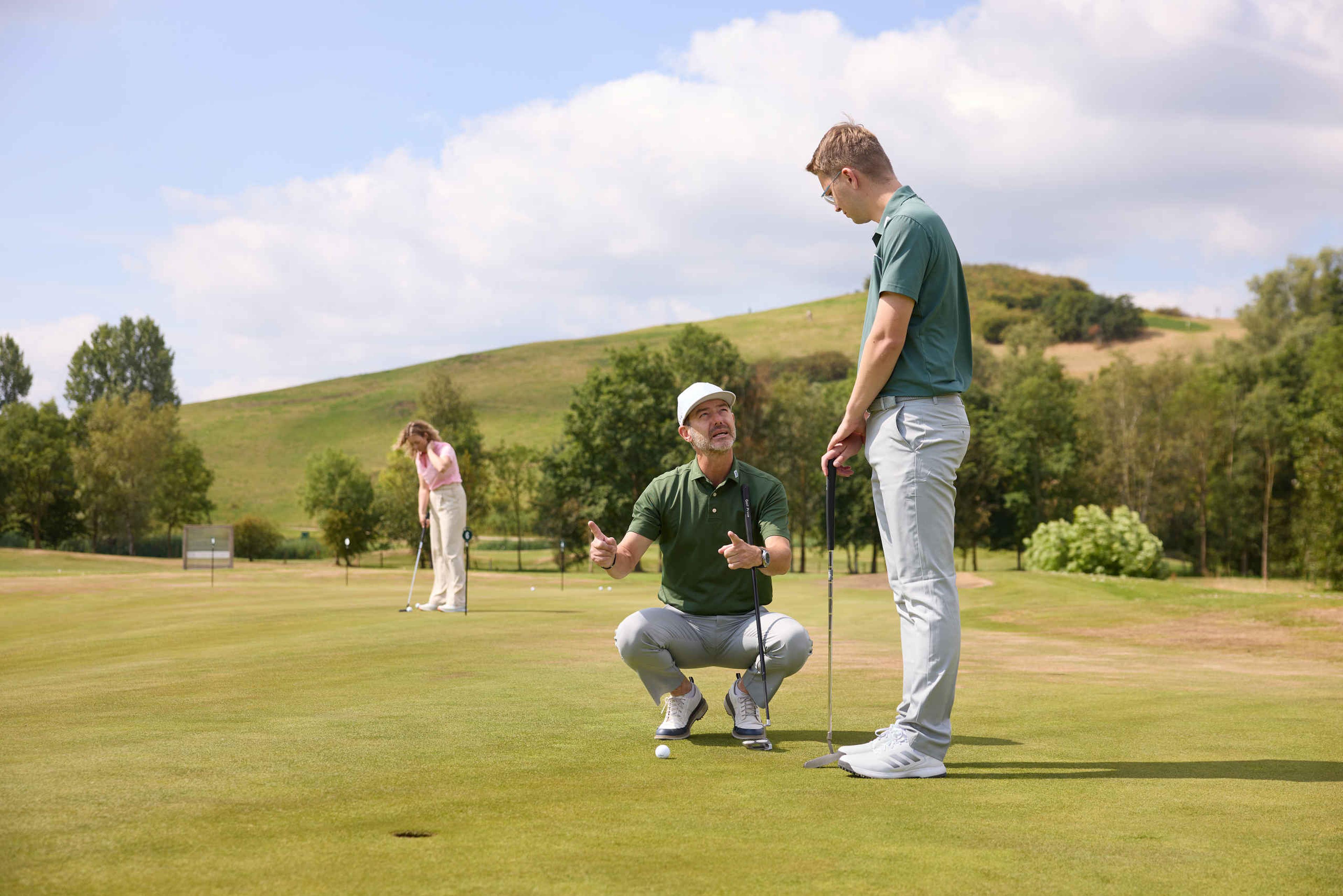 De golfpro van de Golfacademy geeft uitleg aan een man op de puttinggreen van Golf De Gulbergen