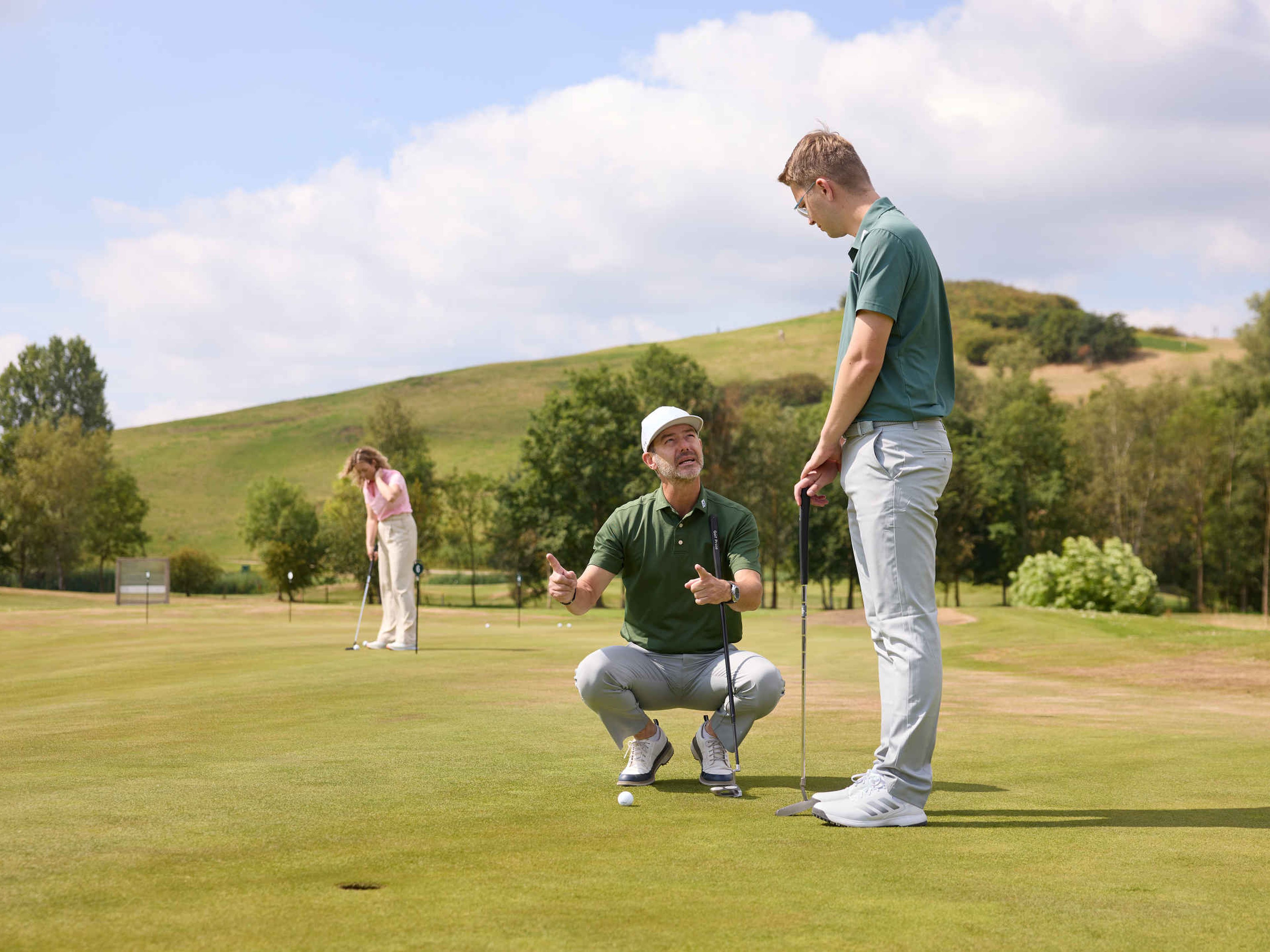 De golfpro van de Golfacademy geeft uitleg aan een man op de puttinggreen van Golf De Gulbergen