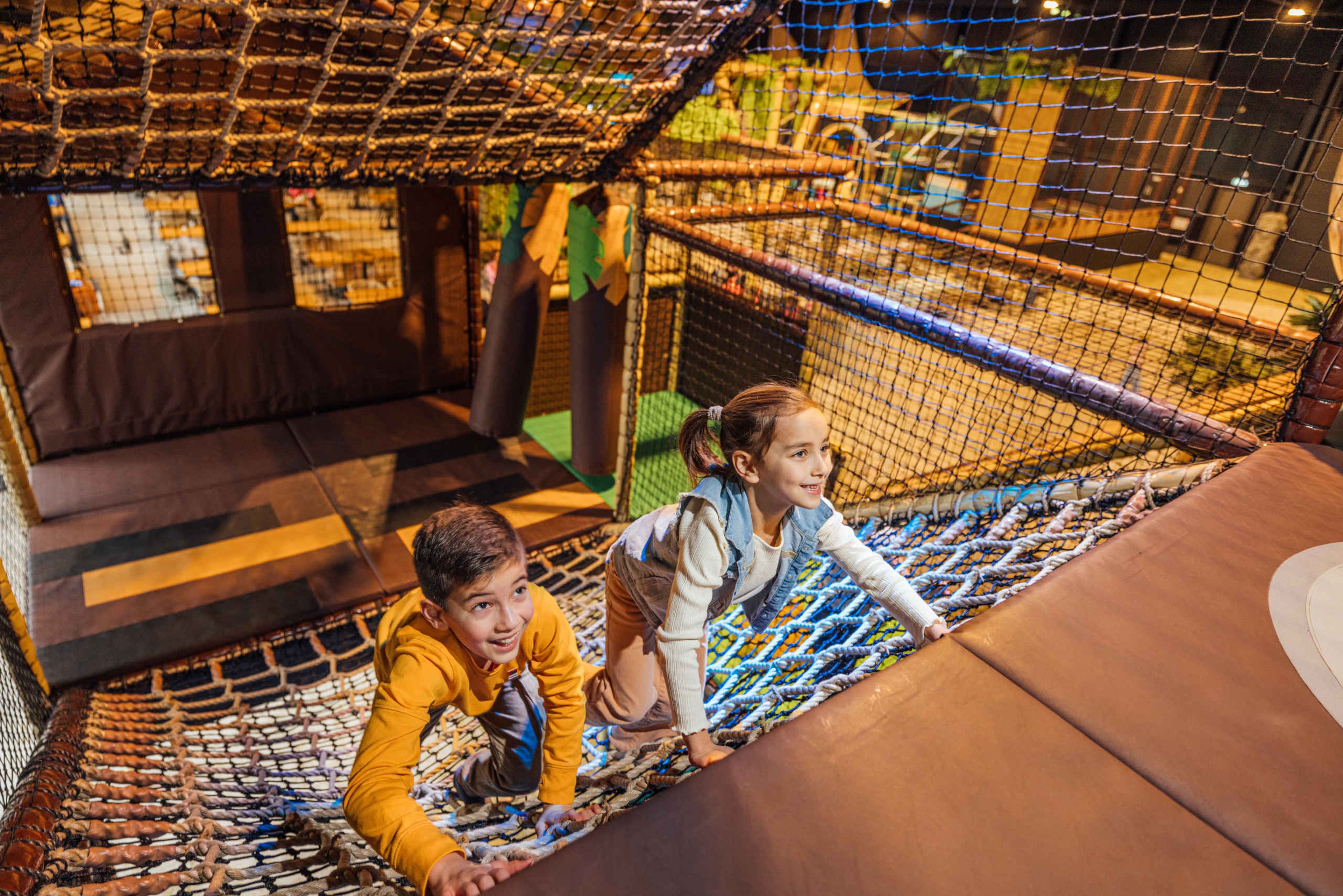 Een jongen en meisje klimmen in het net bij Speelland Indoor bij Beekse Bergen