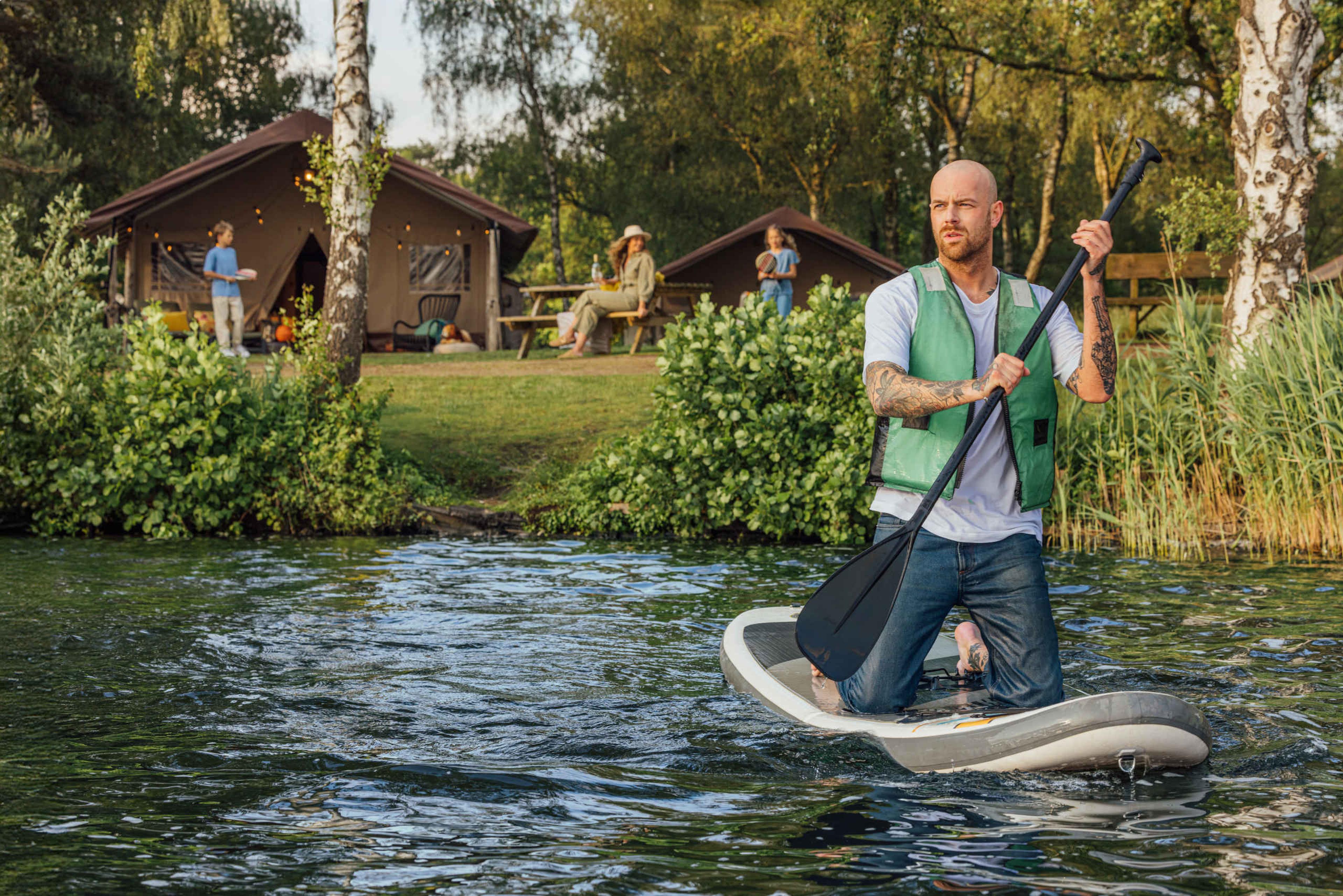 Een man supt op het Victoriameer met op de achtergrond de safaritent met zijn gezin bij Lake Resort Beekse Bergen.