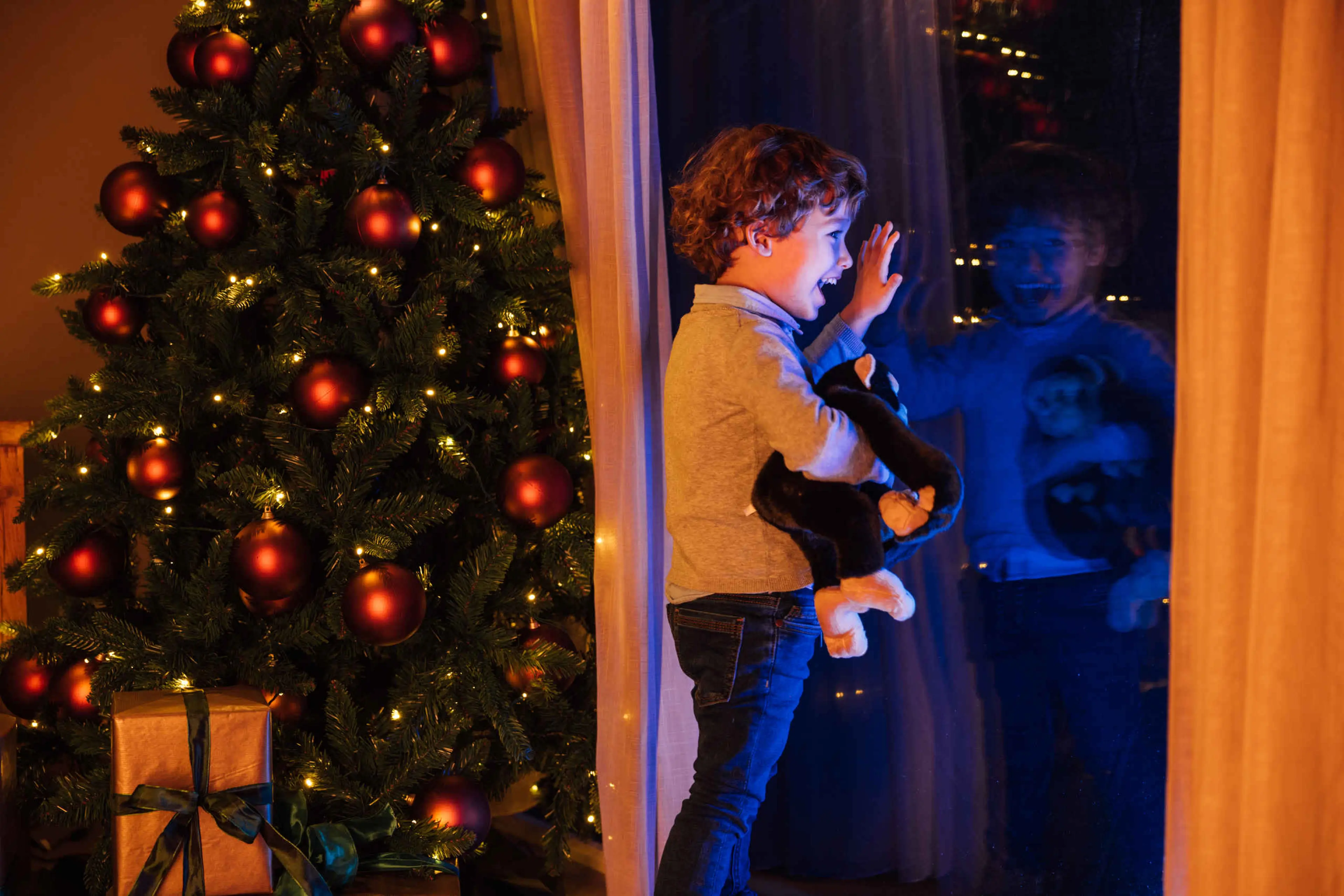 Een jongen kijkt 's avonds uit het raam naar de savanne bij Safari Resort Beekse Bergen.