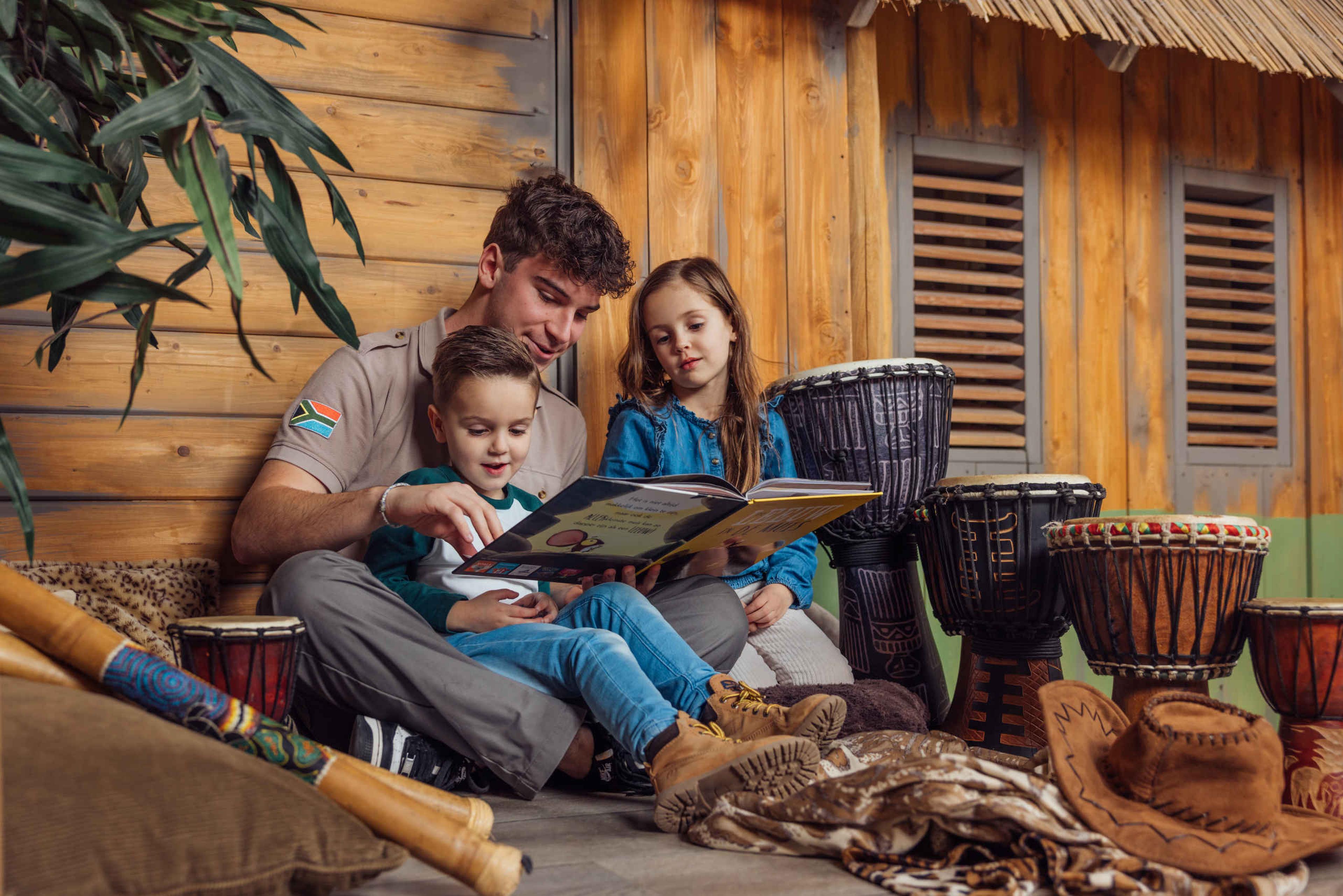 Ranger en kinderen lezen een boek tijdens de animatie in Kodidi Ground bij Lake Resort Beekse Bergen