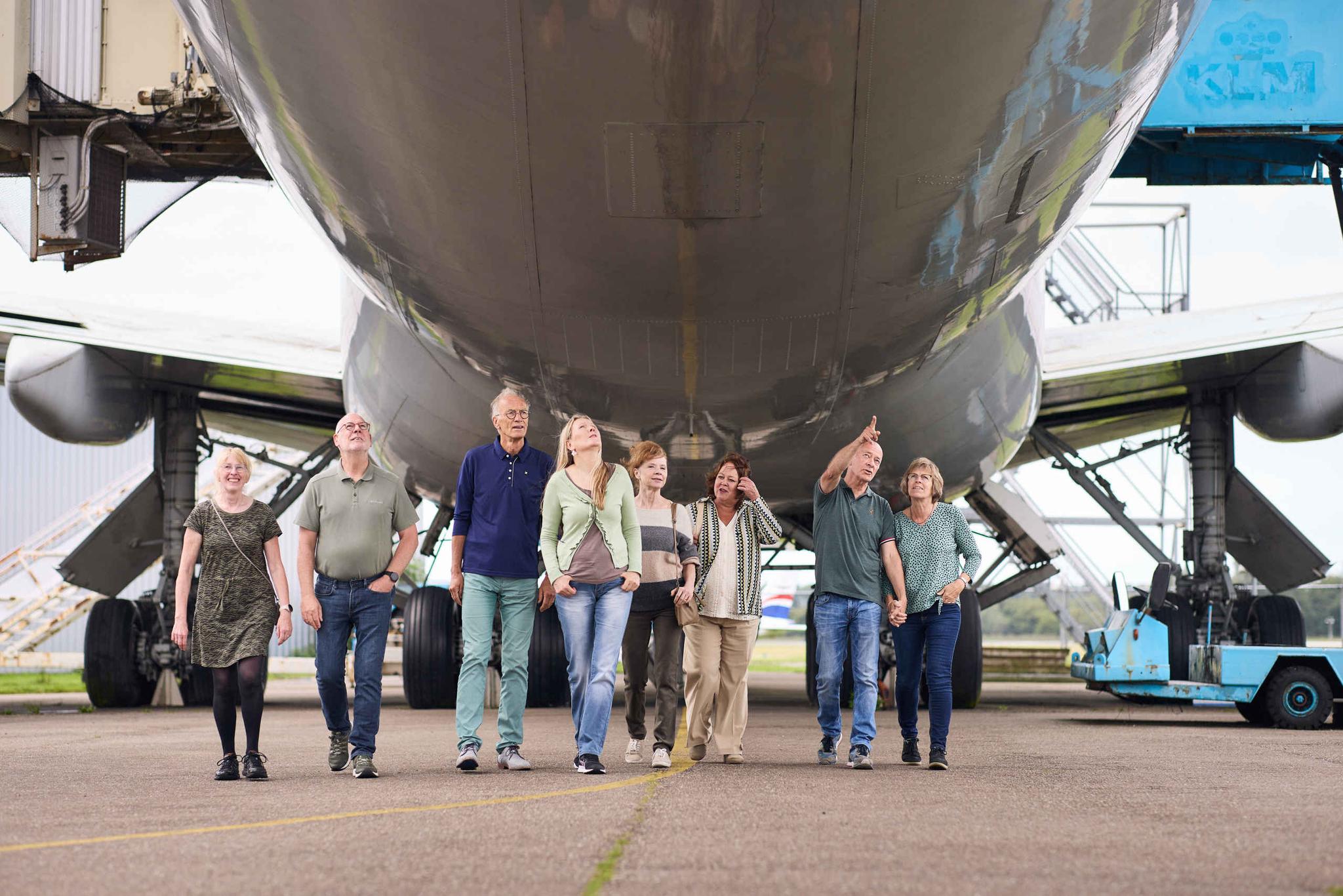 Zorginstellingen senioren lopen onder vliegtuig in Luchtvaartmuseum Aviodrome
