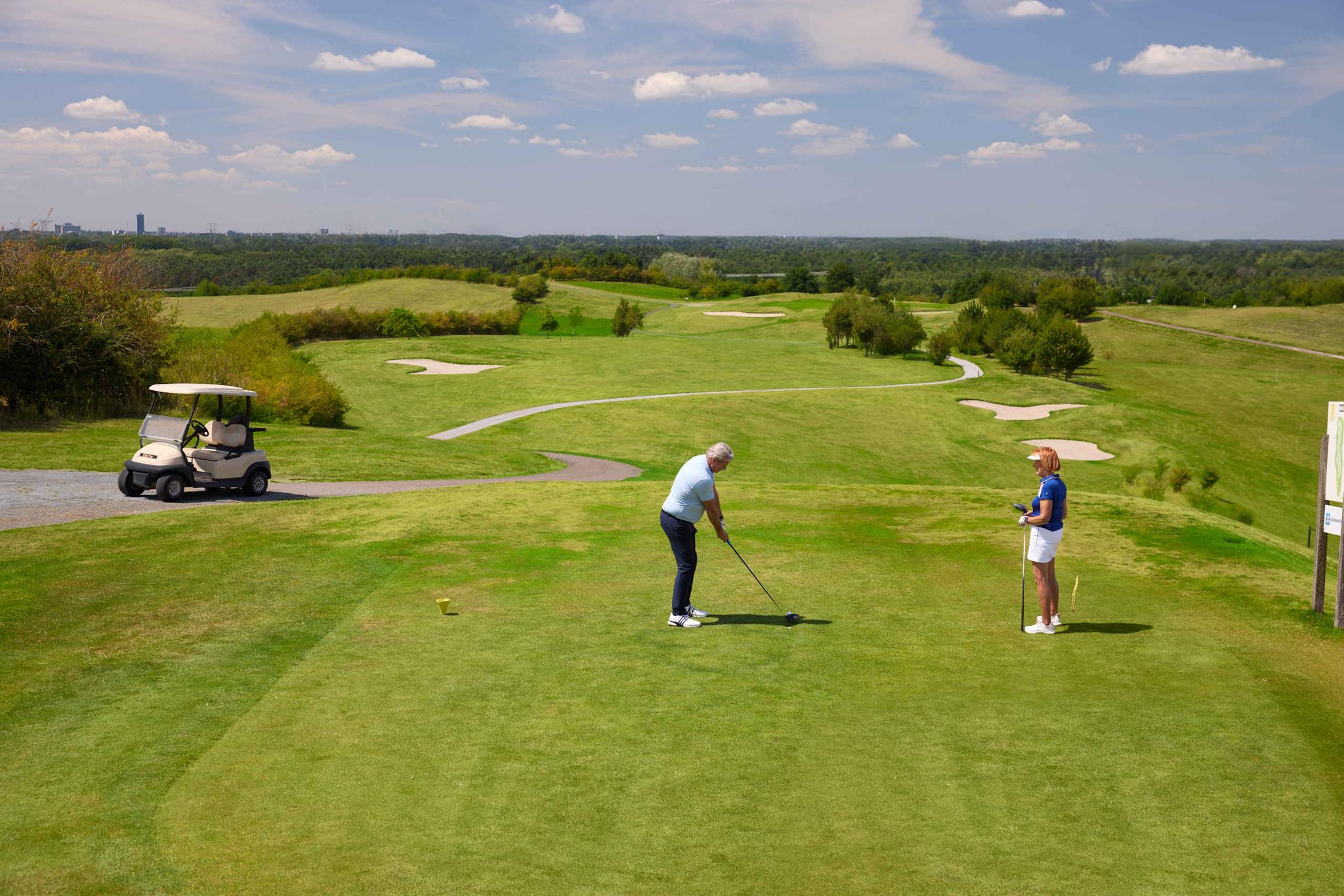 Een man en vrouw slaan af op de teebox van hole 3 op de sprookjesbaan bij Golf De Gulbergen