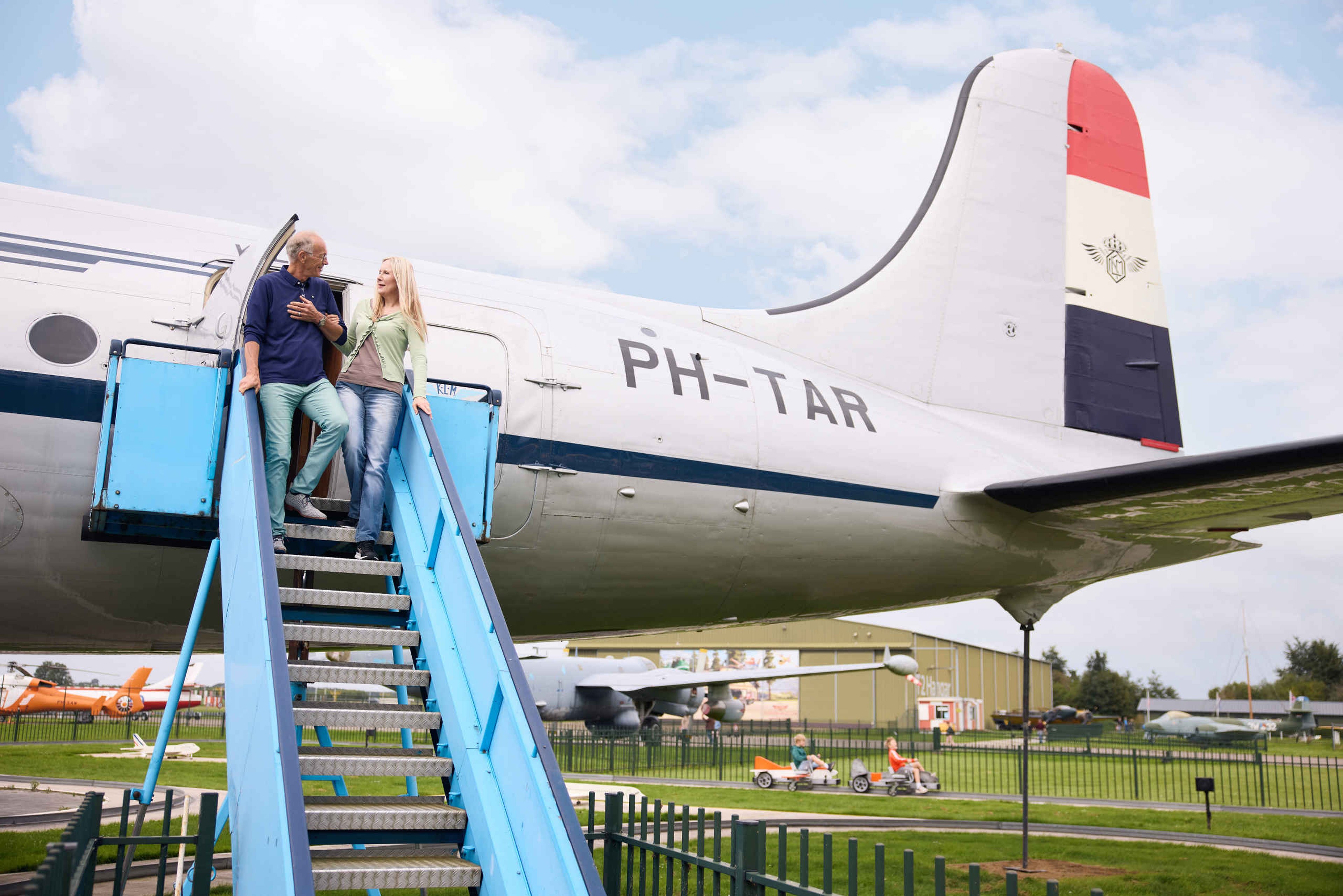 Twee volwassenen lopen uit de PH-TAR op het buitenterrein van Luchtvaartmuseum Aviodrome
