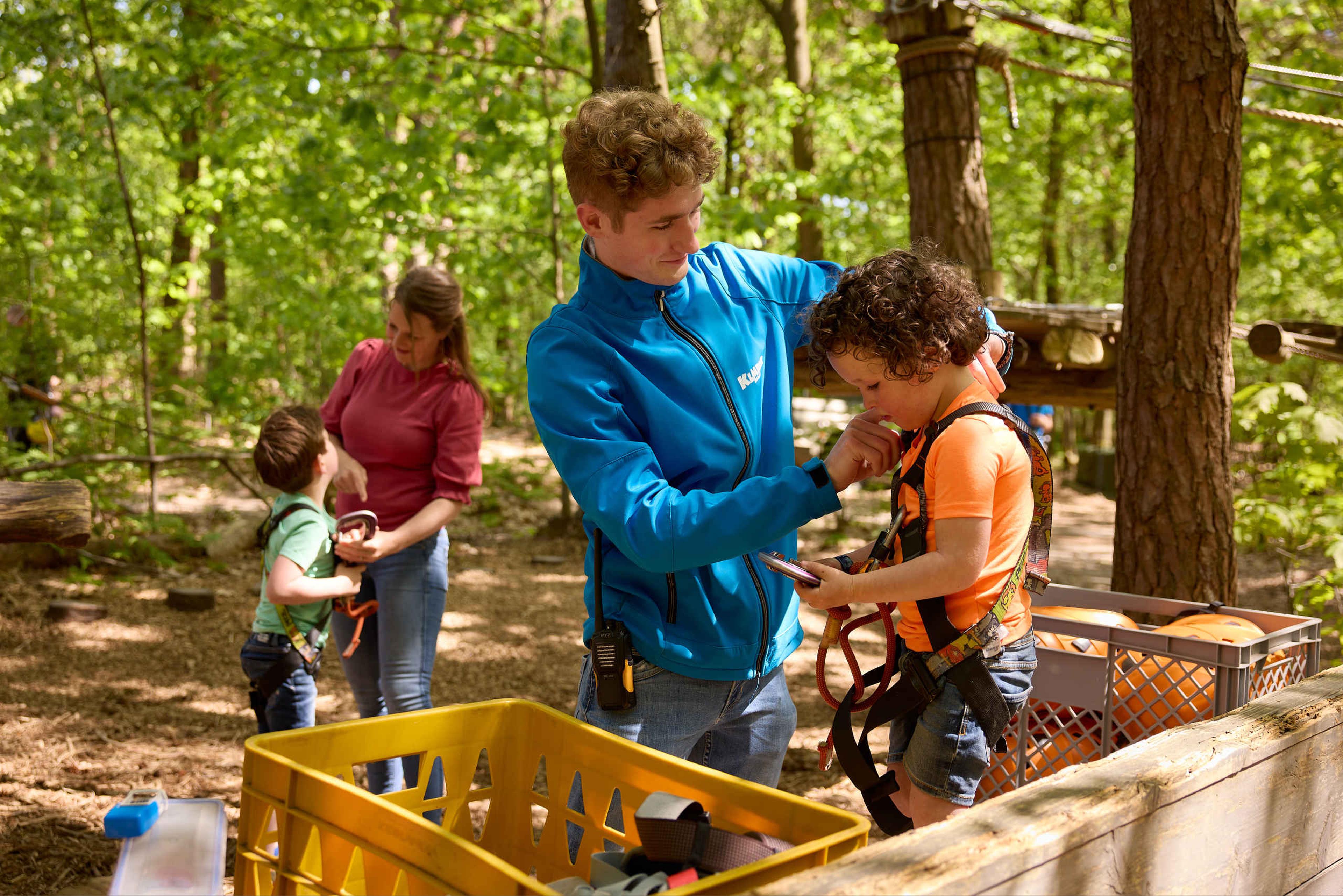 Een instructeur zorgt dat de beugels goed vast zitten bij een kind voordat hij gaat klimmen bij Klimrijk Brabant.