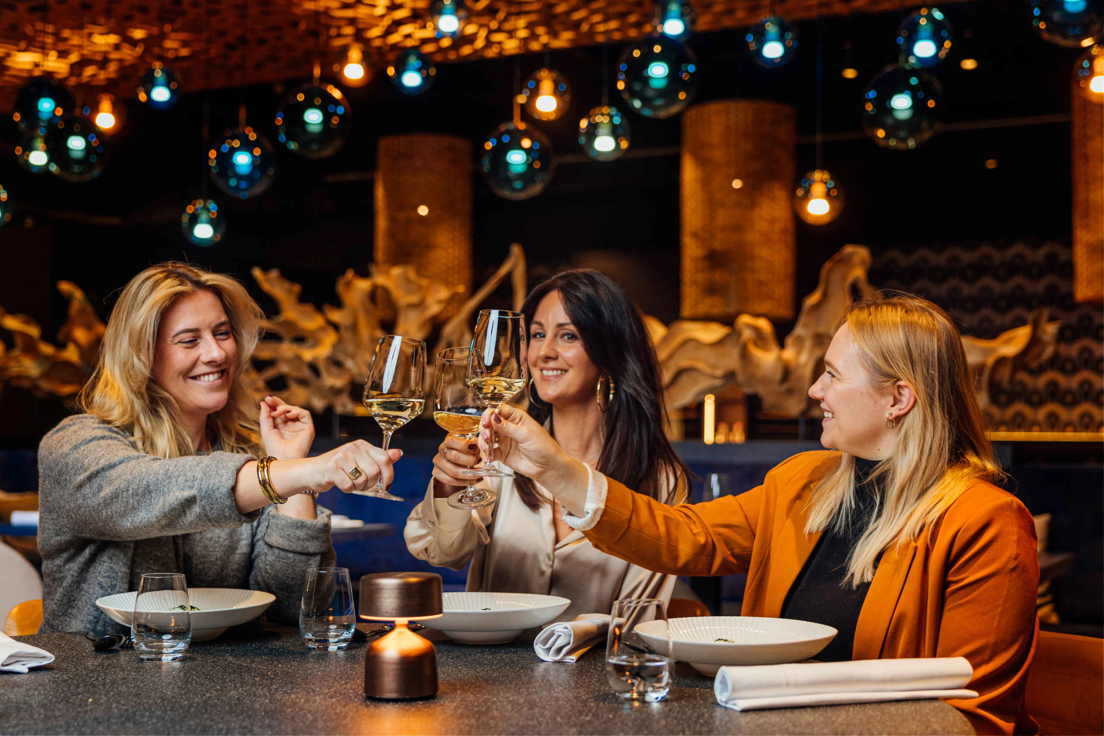Drie collega's proosten met een glas wijn bij Bar & Restaurant Nommos.