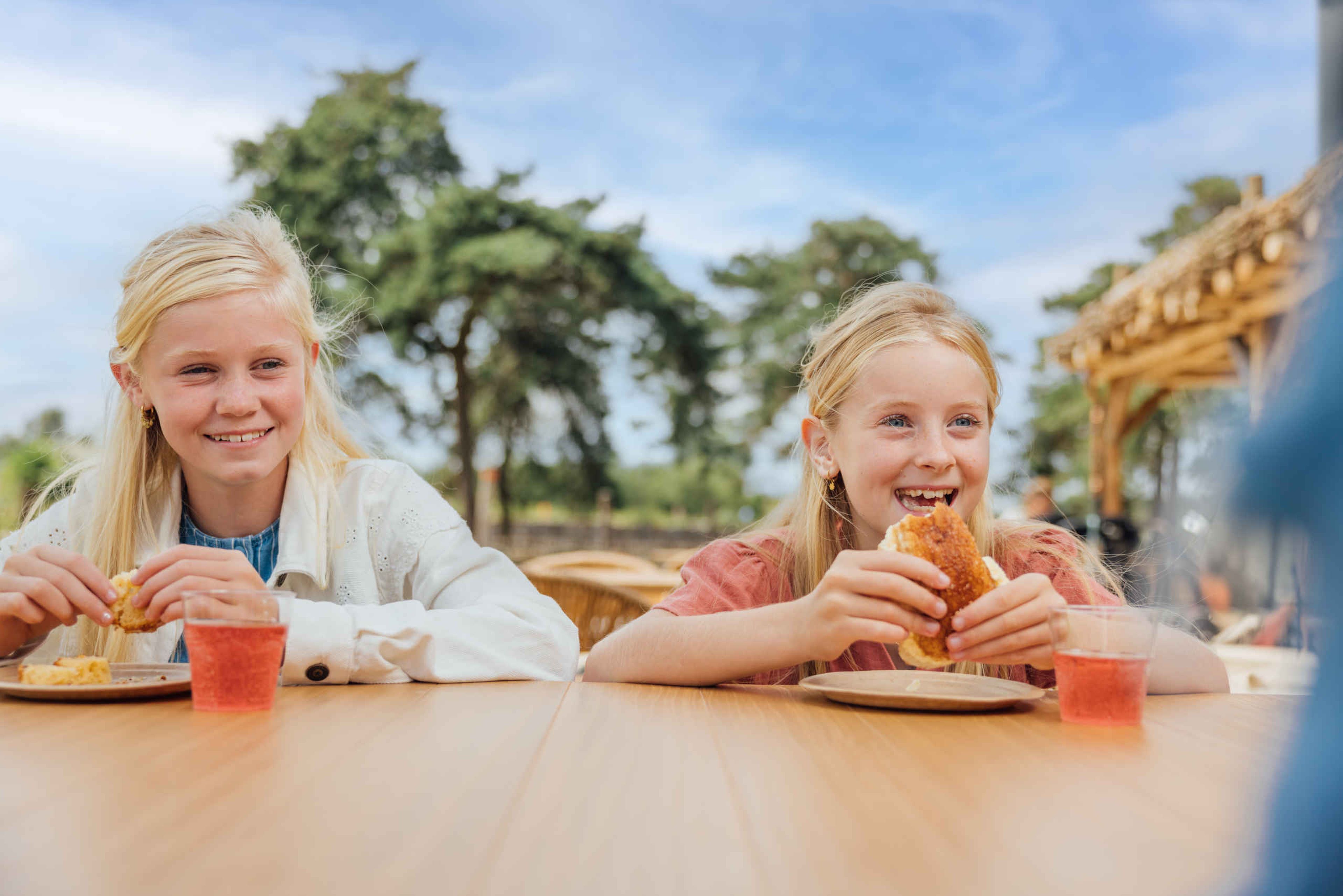 Meisjes eten op terras buiten bij restaurant Mugunda in Afrikadorp bij Safaripark Beekse Bergen