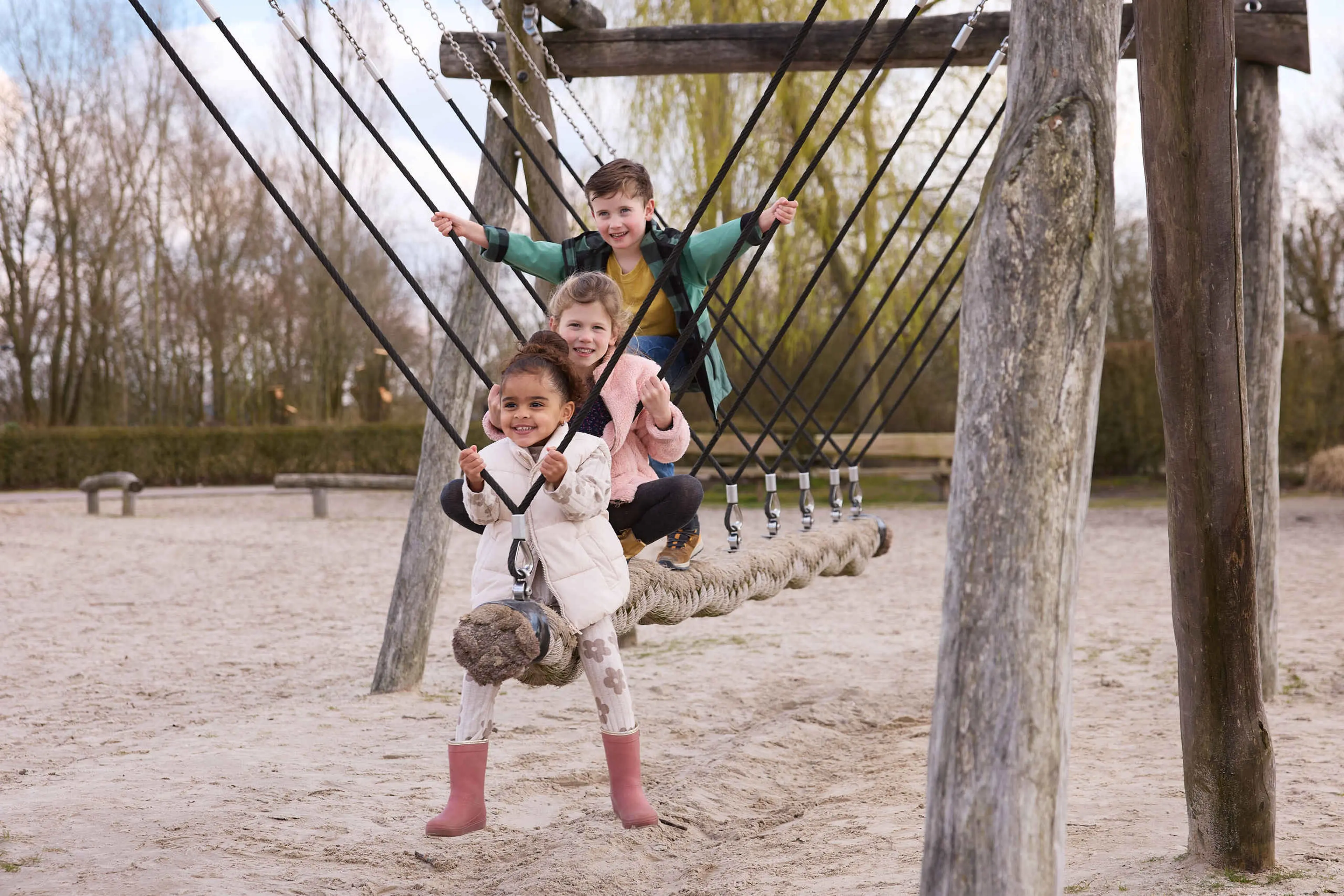 Drie kinderen op een schommel in de speeltuin in Eindhoven Zoo.