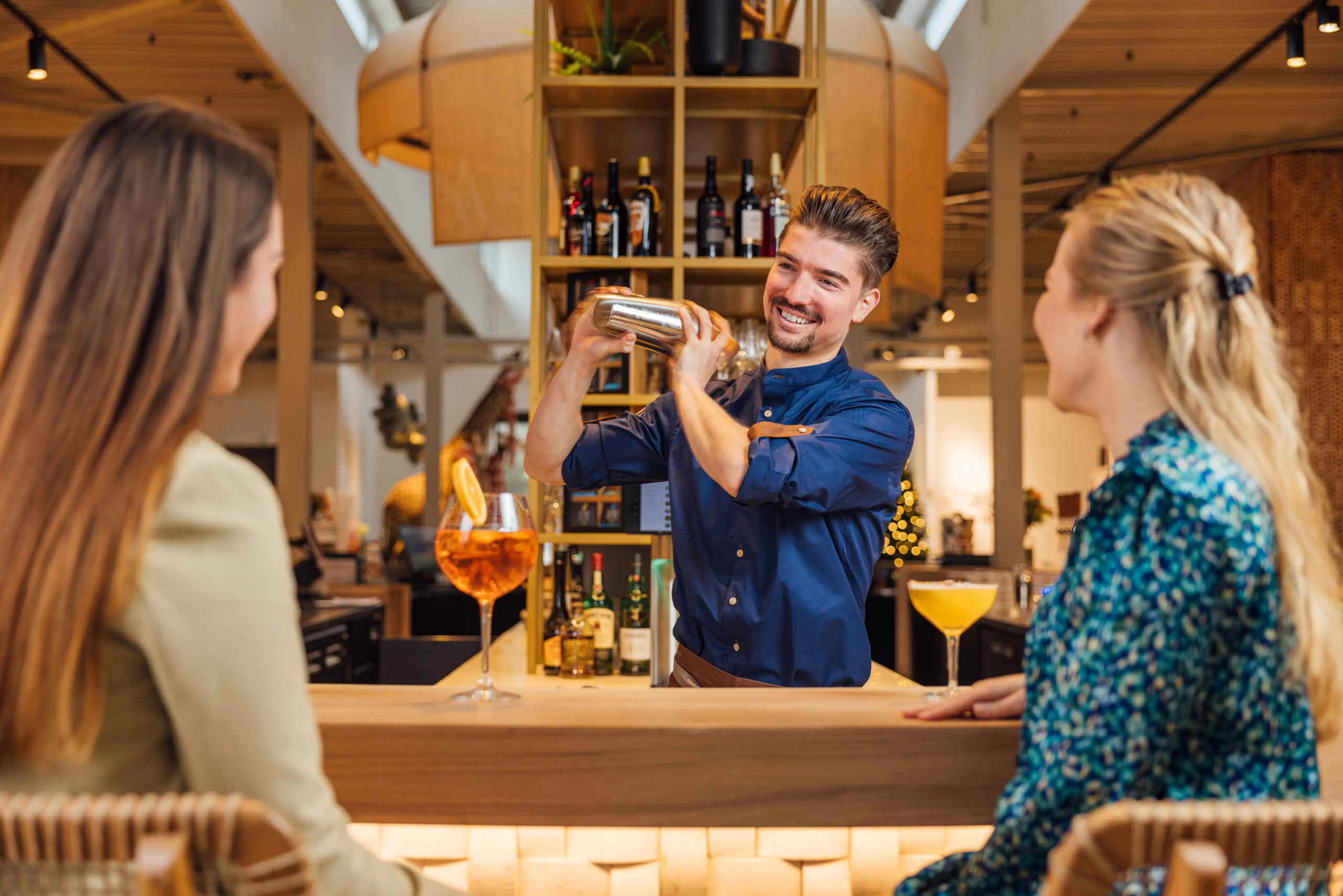 Een barman is cocktails aan het shaken voor twee gasten bij Hogon Bar bij Safari Hotel Beekse Bergen.