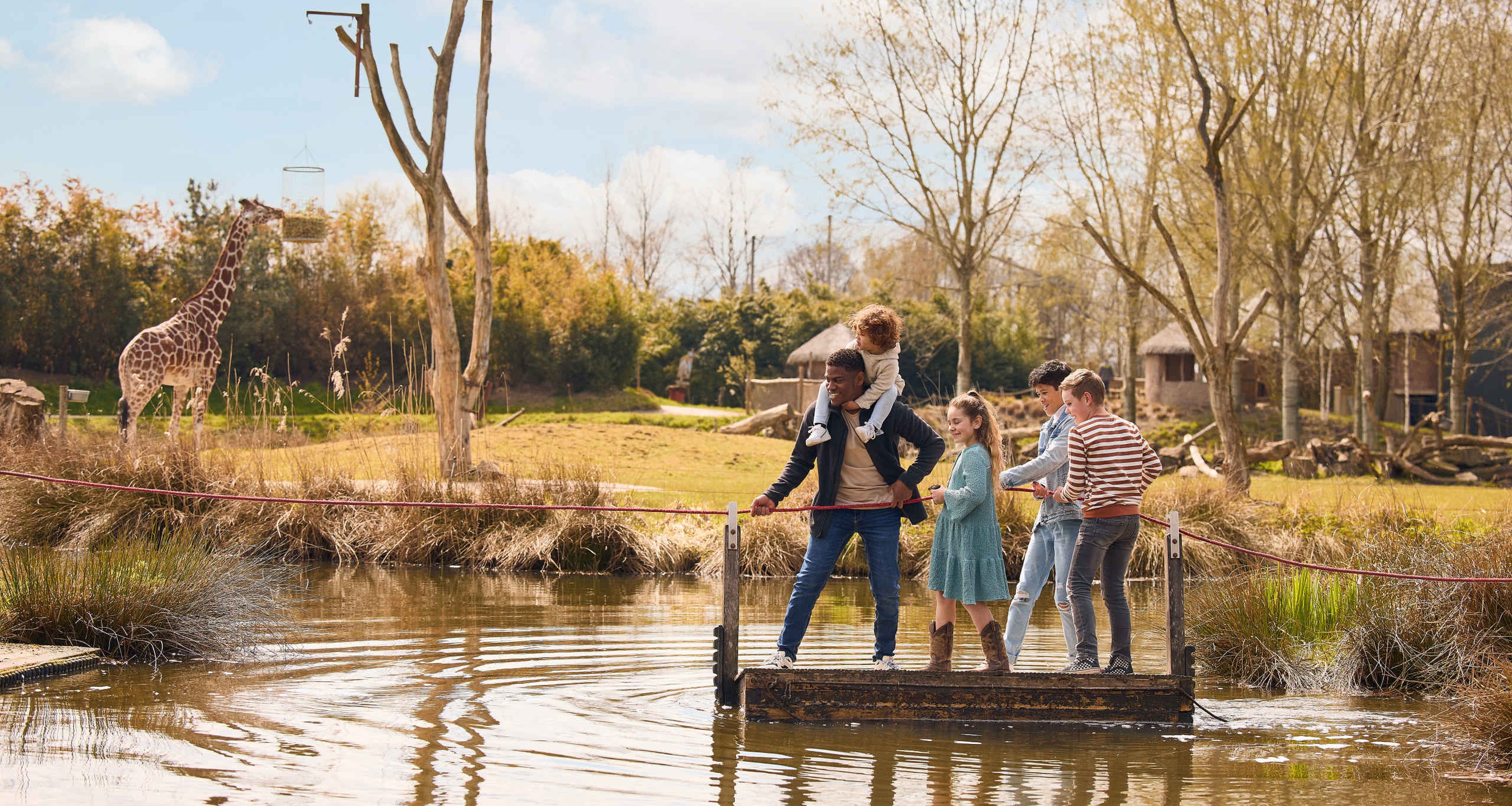 Gezin op een vlot bij een giraffe in ZooParc Overloon