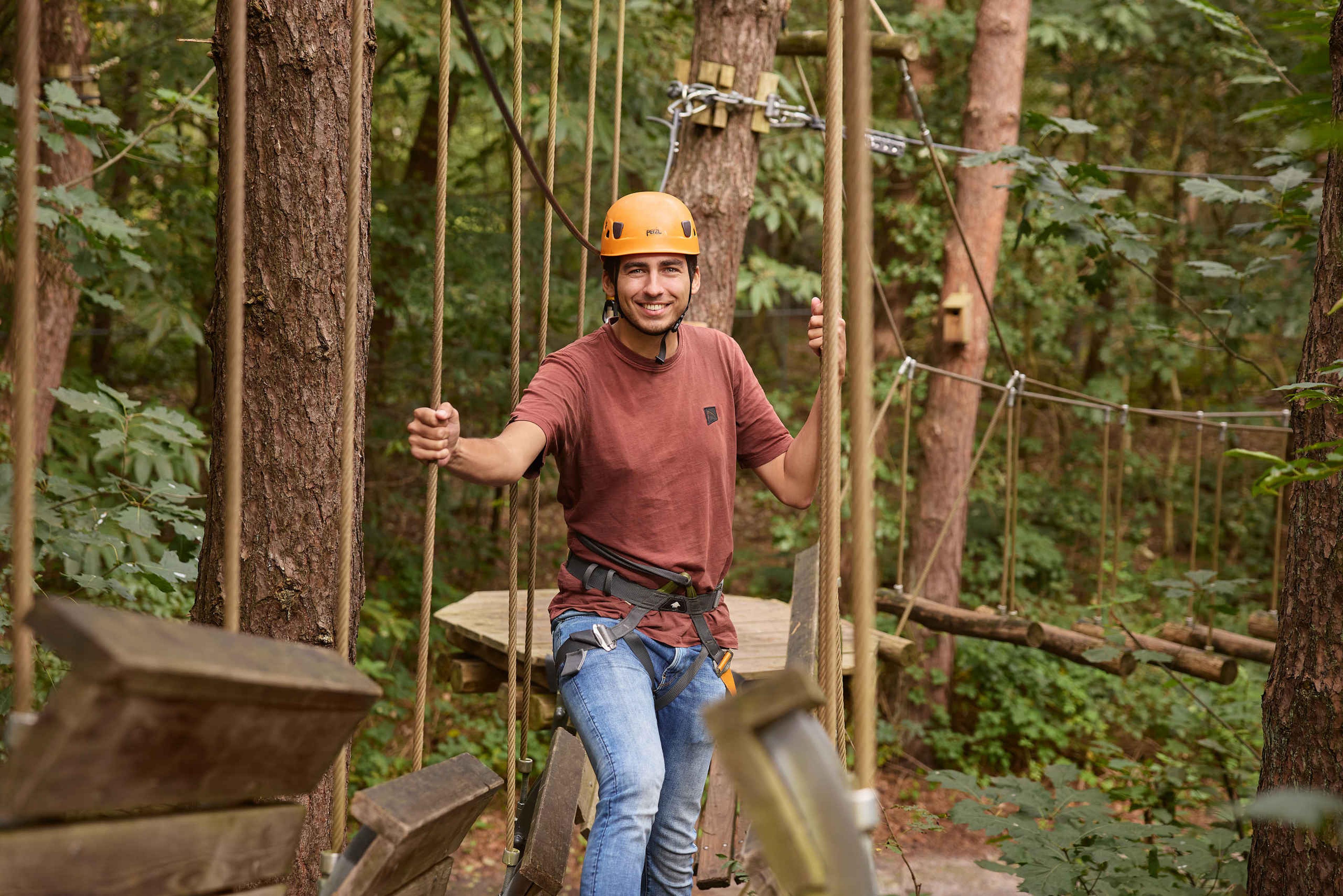 Een man klimt tussen de touwen op het klimparcours van Klimrijk Brabant