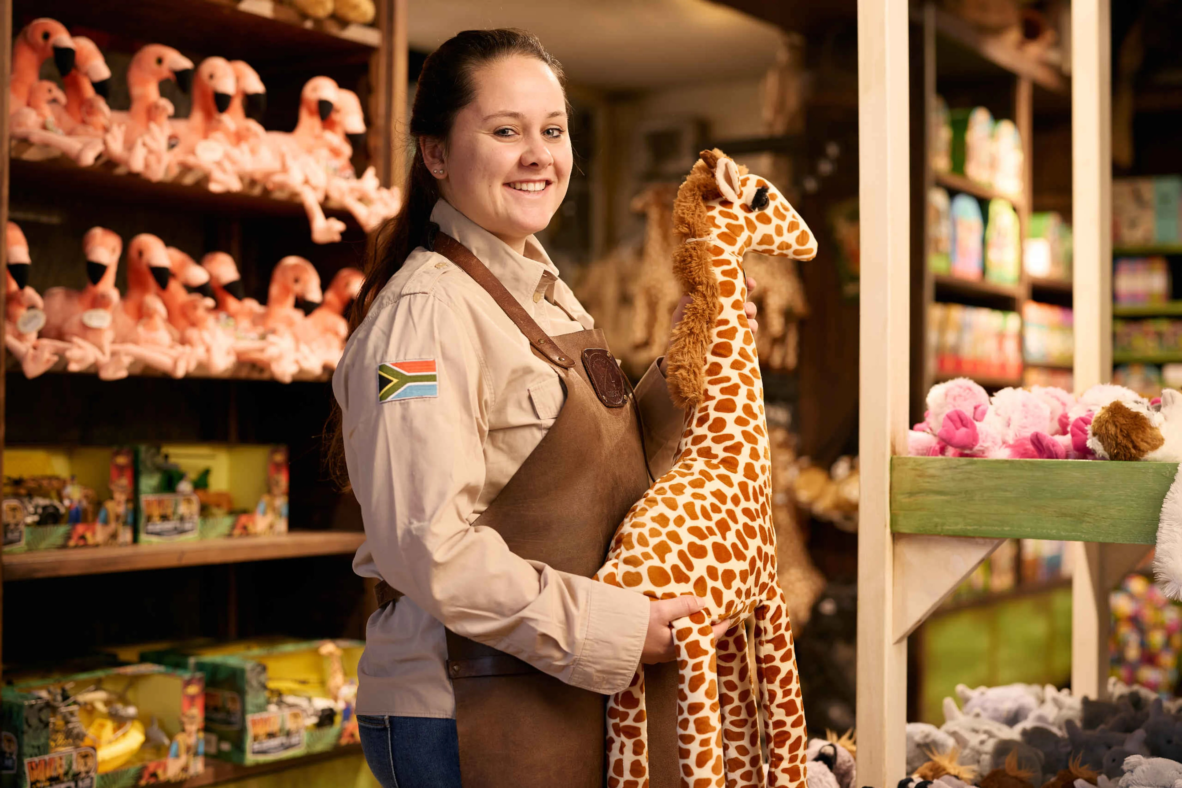 Souvenirwinkel medewerker heeft een knuffel in de vorm van een giraf vast Safaripark Beekse Bergen