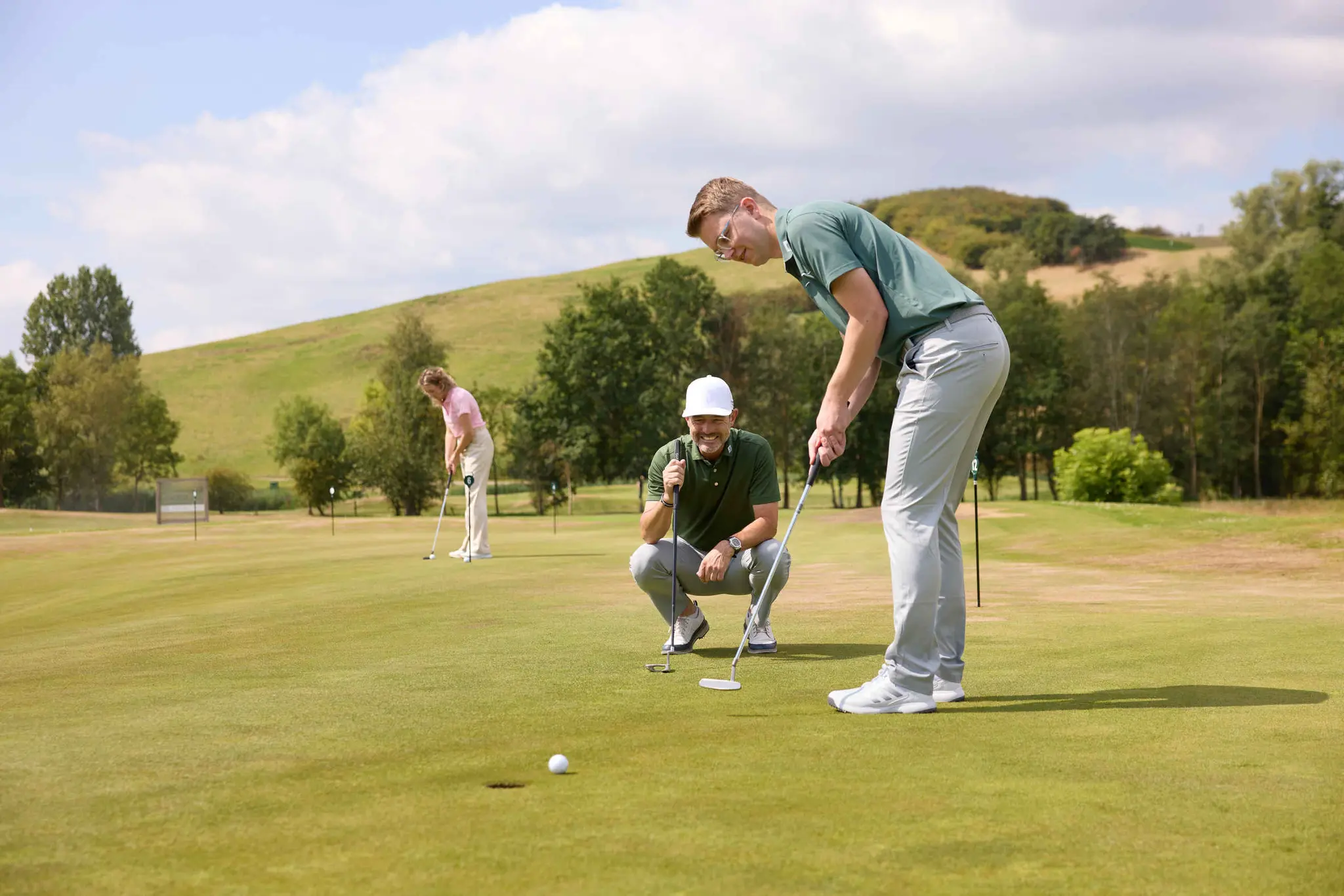 Een man putt zijn bal terwijl de golfpro van de golfacademy toekijkt op de puttinggreen van Golf De Gulbergen