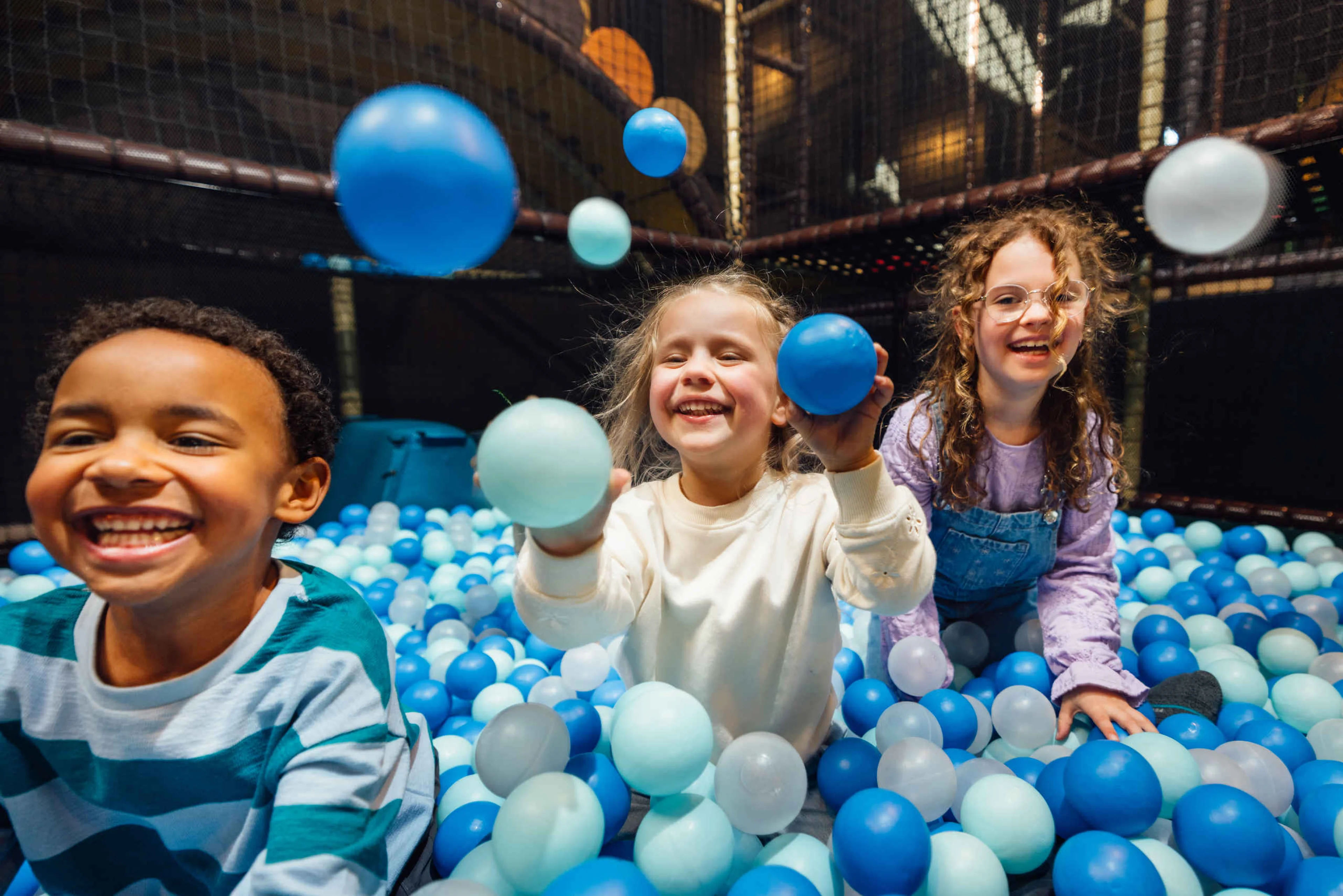 Drie kinderen in de ballenbak bij Speelland Indoor