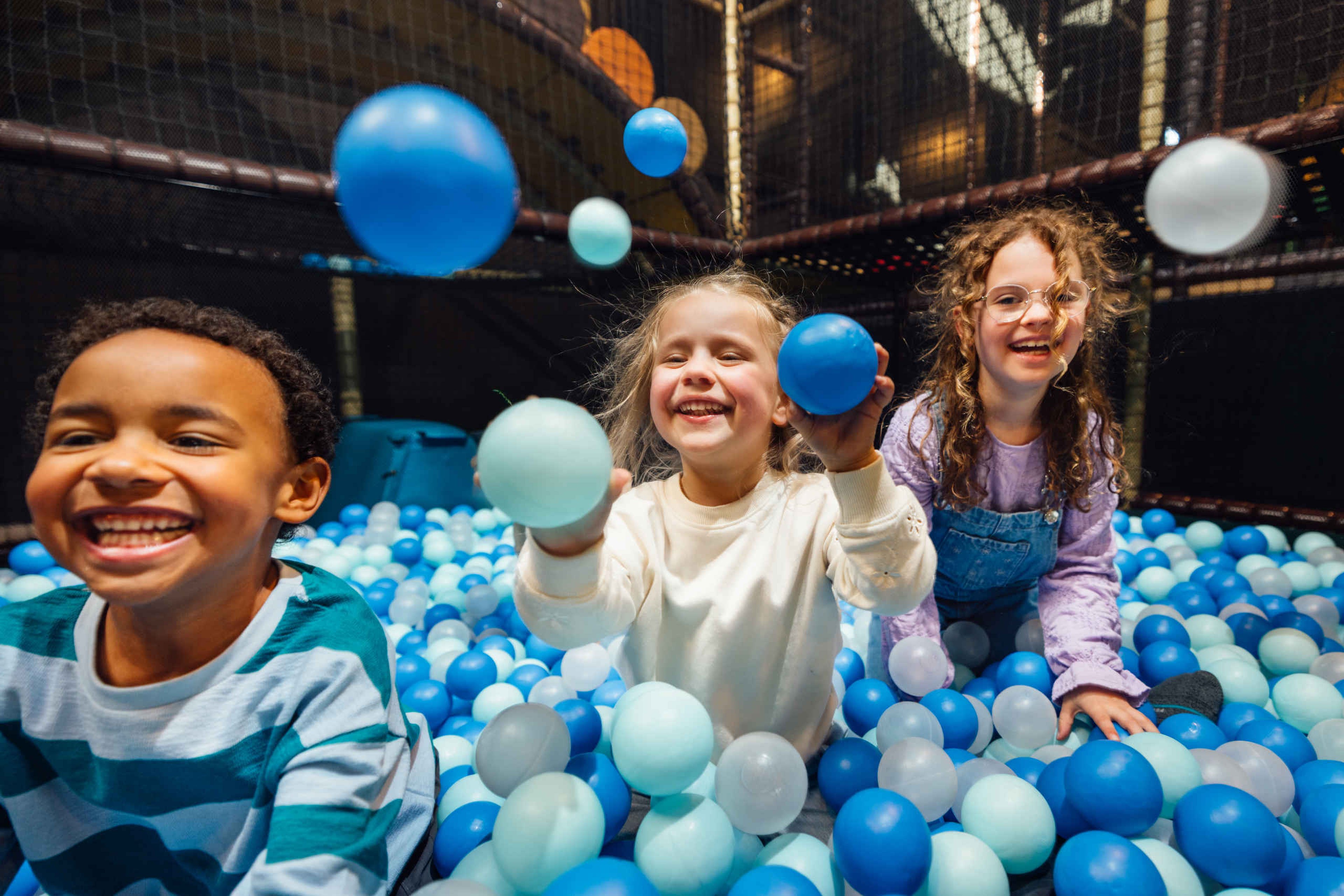 Drie kinderen in de ballenbak bij Speelland Indoor