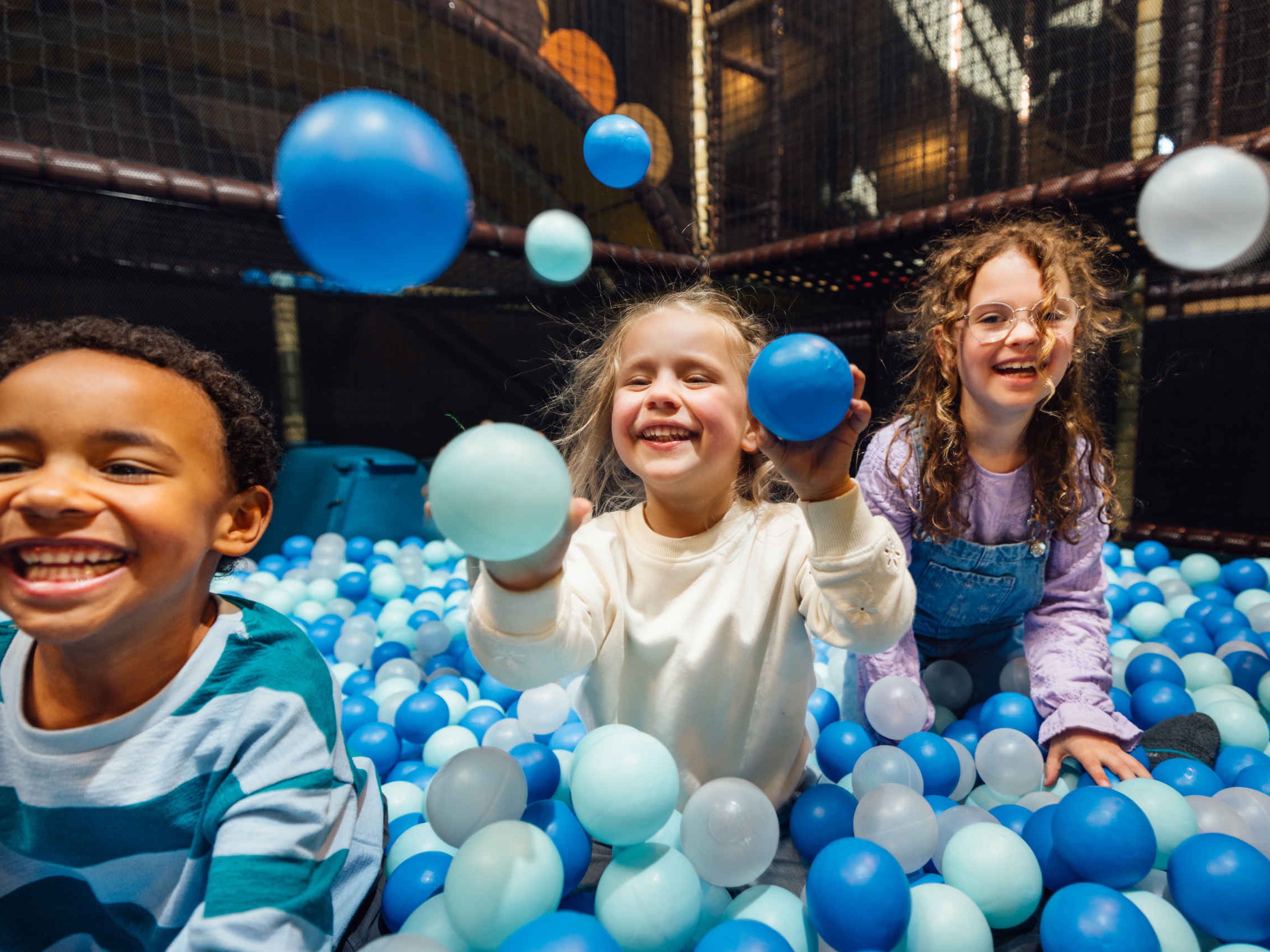 Drie kinderen in de ballenbak bij Speelland Indoor