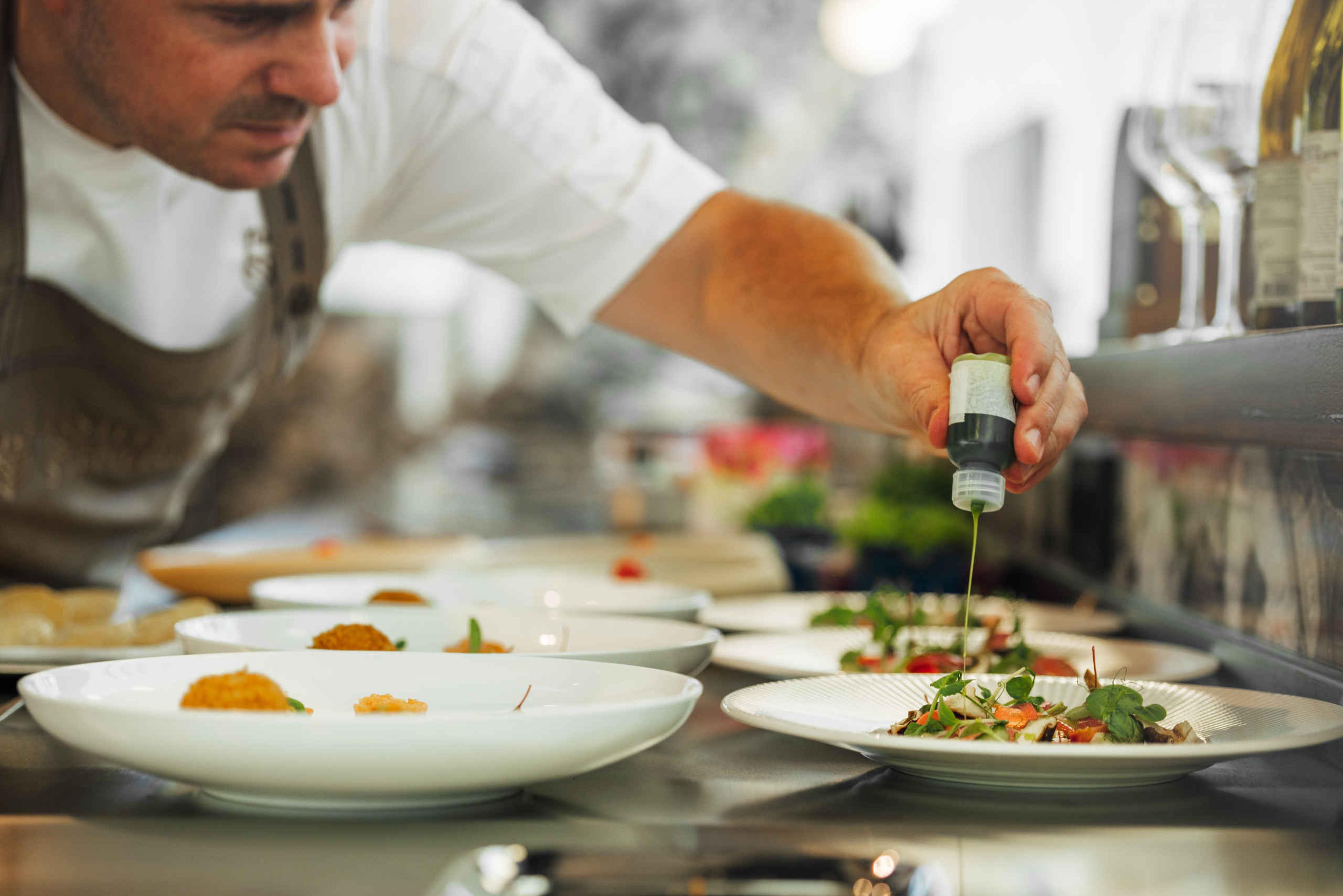 Kok schenkt dressing in Restaurant Orangerie Kasteel Steenenburg