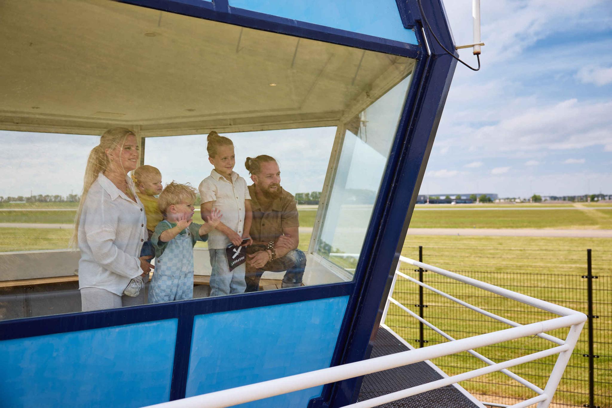 Een gezin in de verkeerstoren met uitzicht op de landingsbaan bij Luchtvaartmuseum Aviodrome