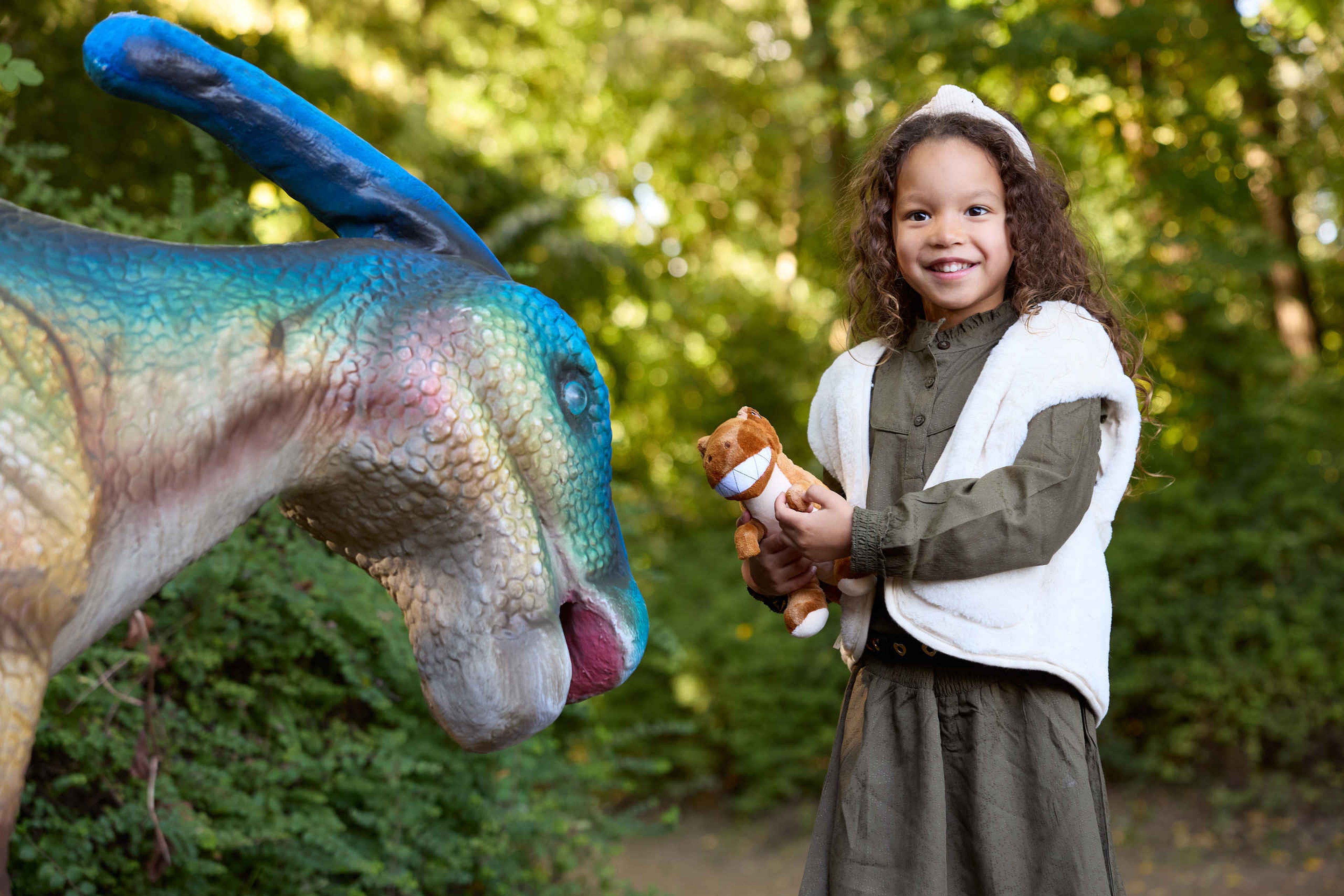 Meisje met knuffel in handen bij dino in ZooParc Overloon