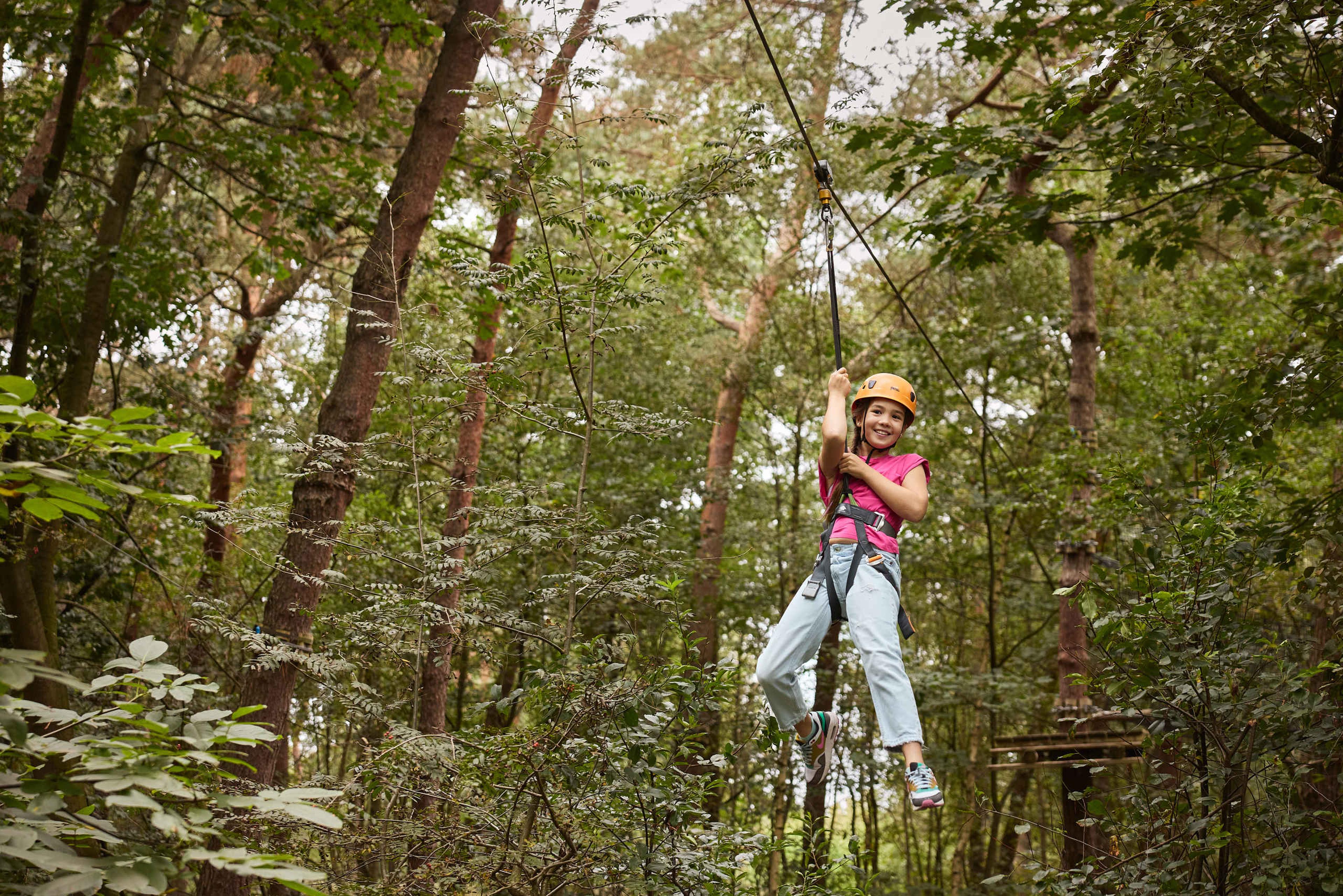 Een meisje gaat van de ziplijn op het klimparcours bij Klimrijk Brabant.
