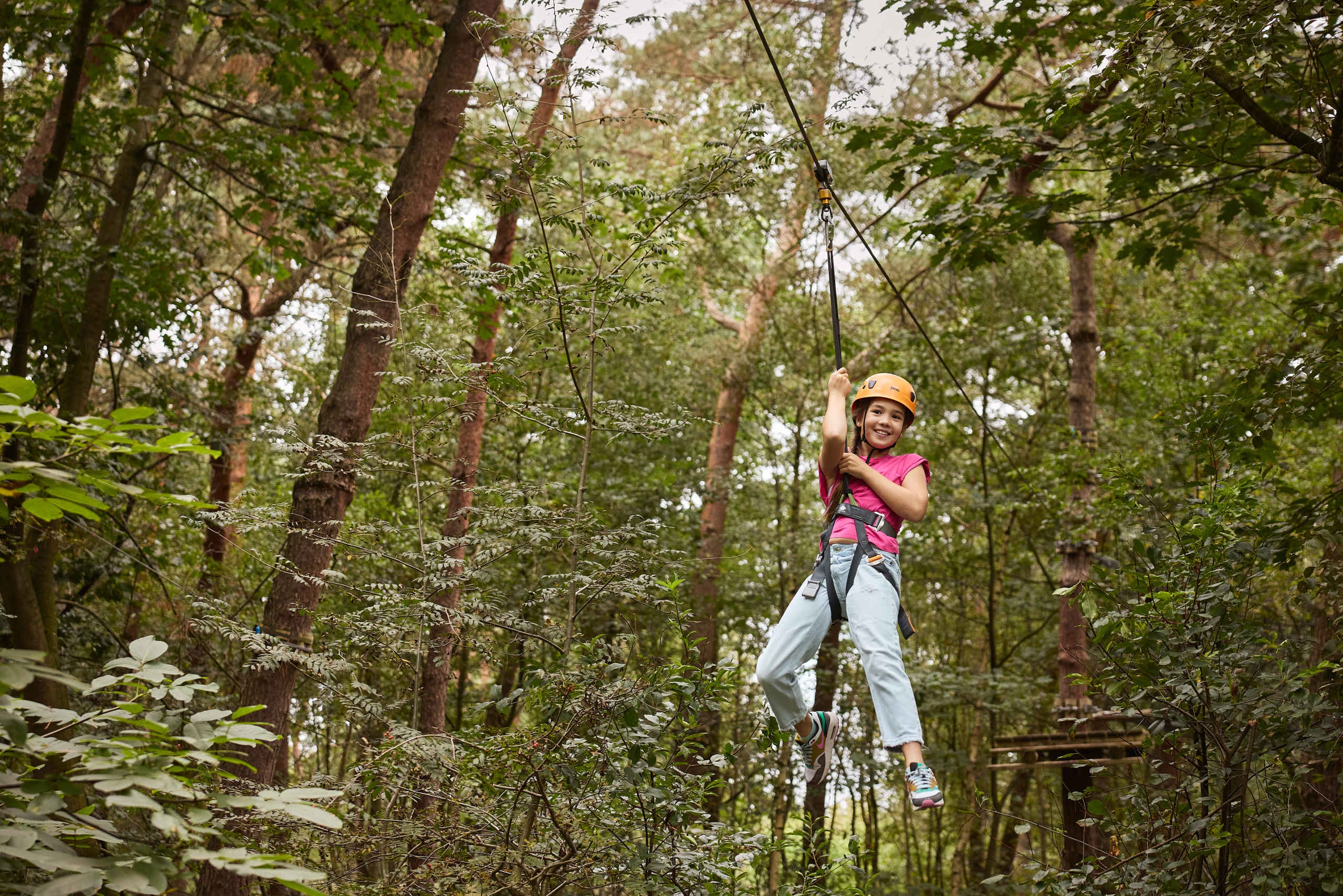 Een meisje gaat van de ziplijn op het klimparcours bij Klimrijk Brabant.