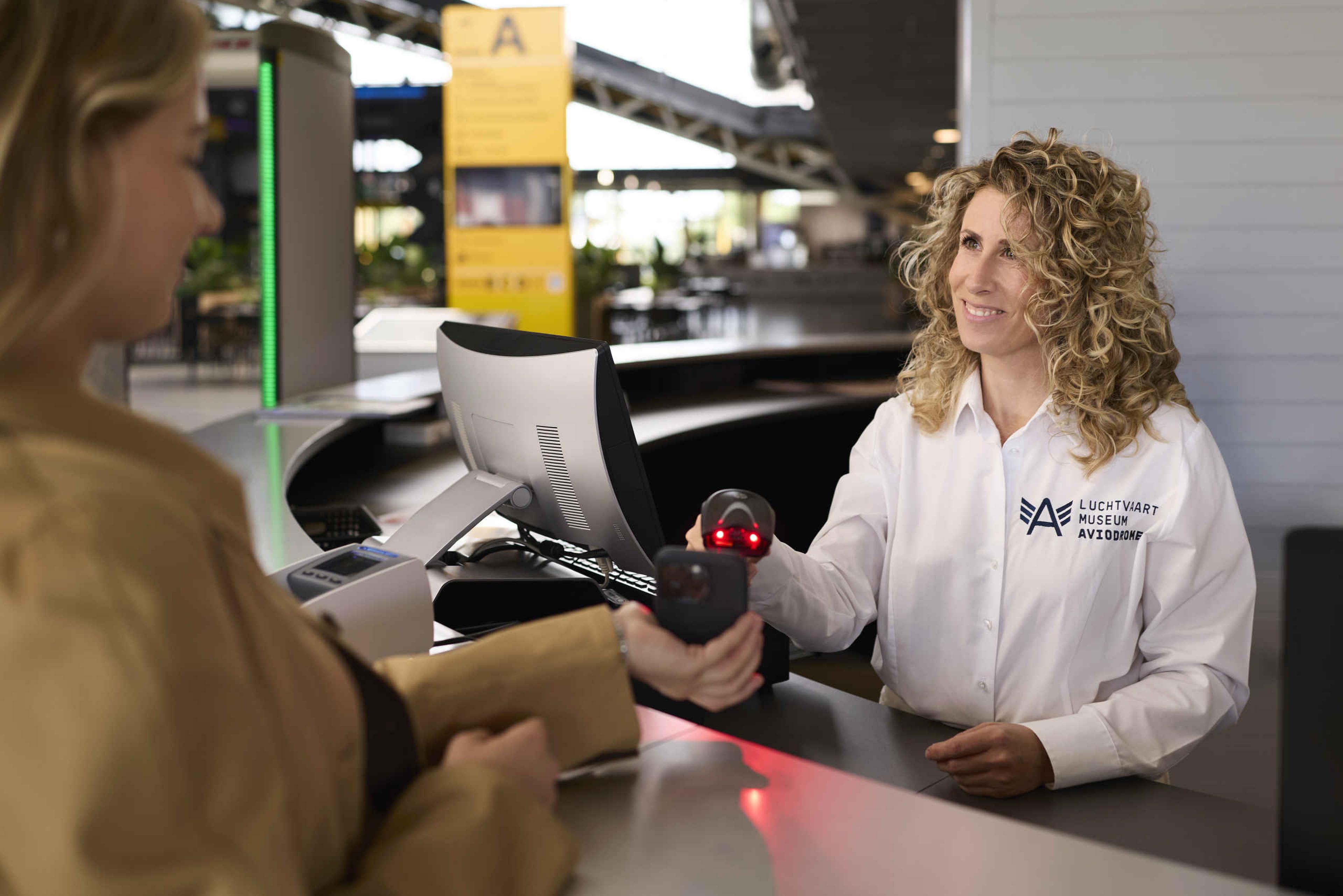 Een kassamedewerkers scant het online ticket van een bezoekers in Luchtvaartmuseum Aviodrome.