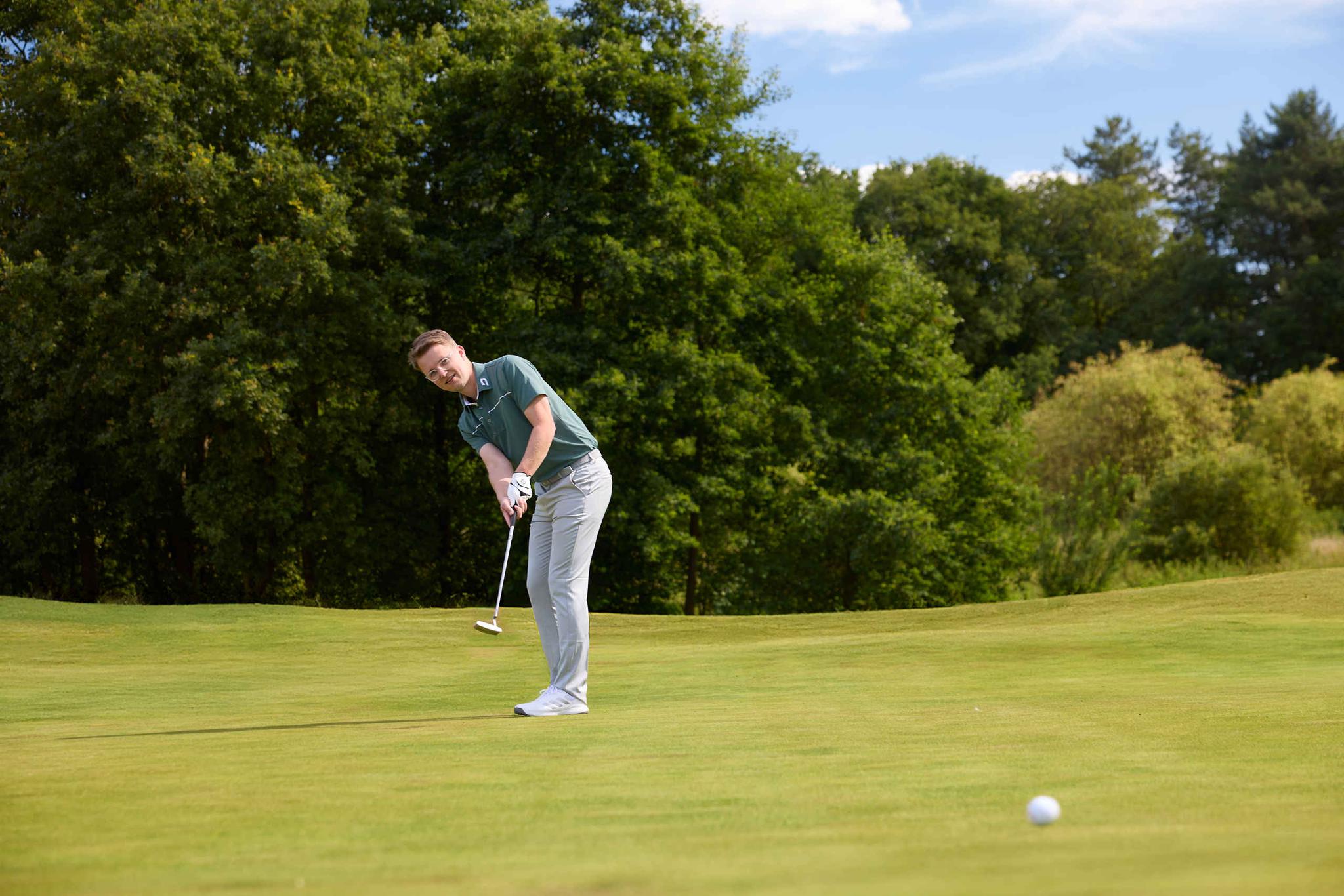 Een man putt zijn golfbal op de green van hole 15 op de libellebaan bij Golf De Gulbergen