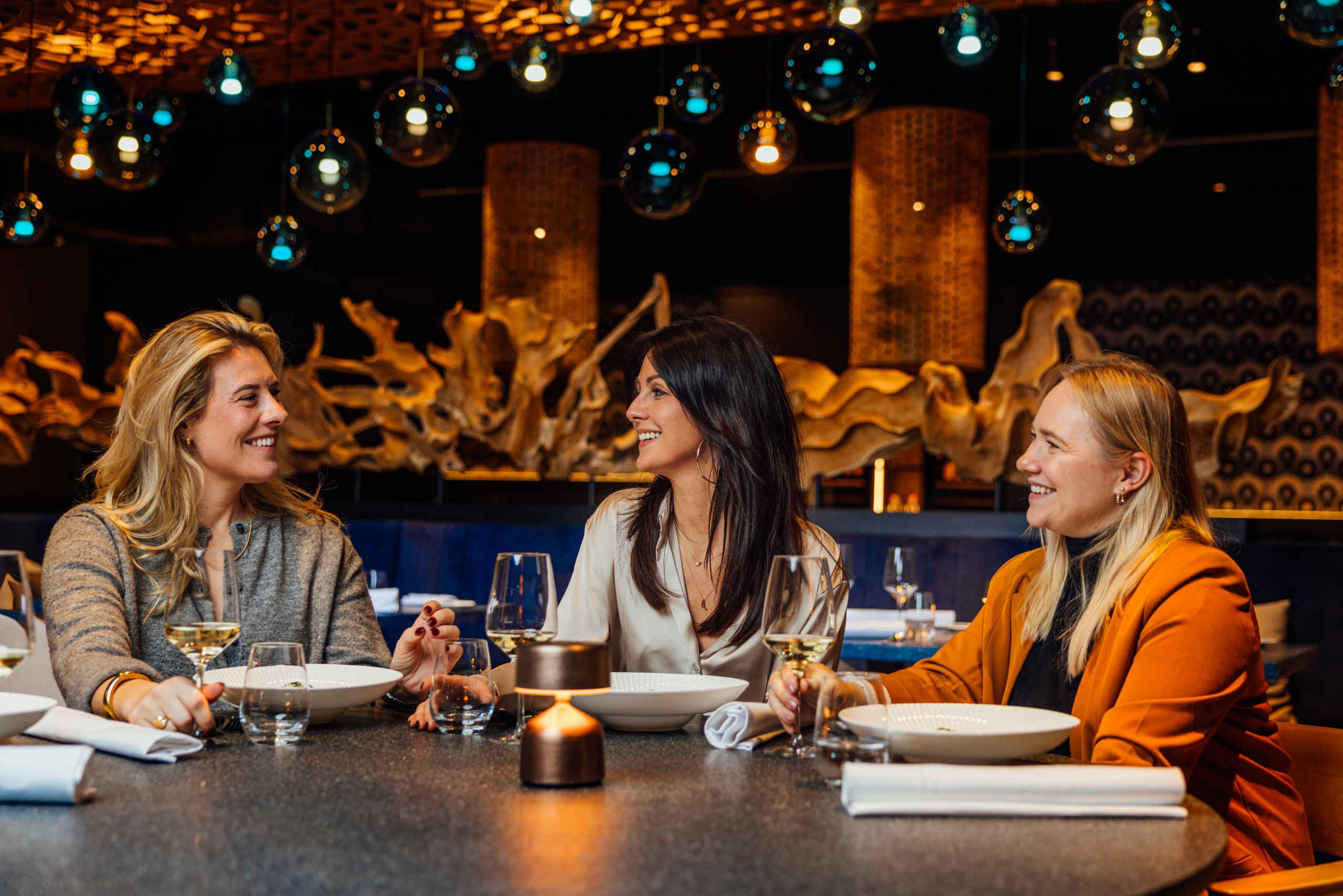 Drie collega's drinken wijn en dineren bij Bar & Restaurant Nommos.