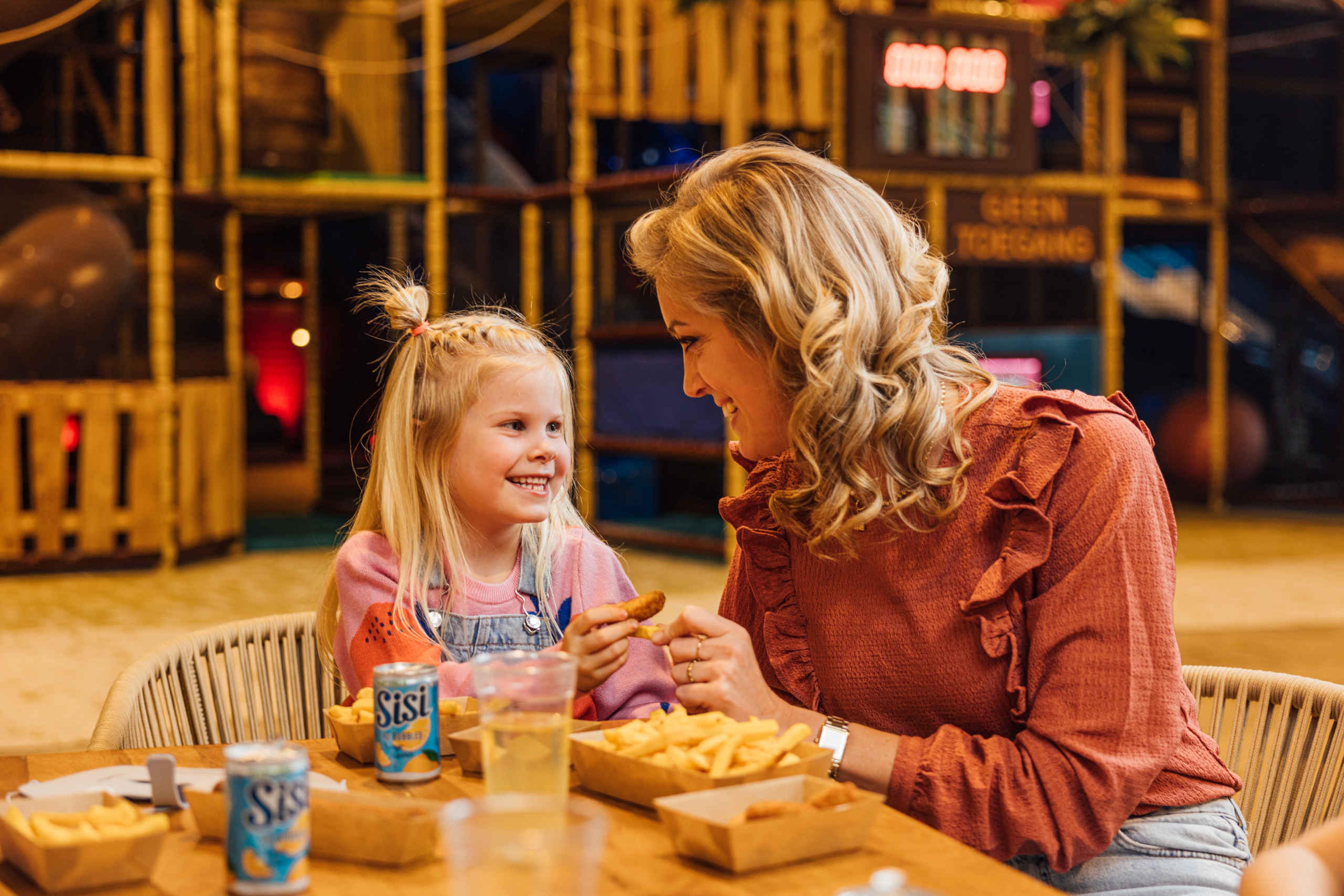 een moeder en dochter genieten van een frietje met snacks en drinken in Speelland Indoor