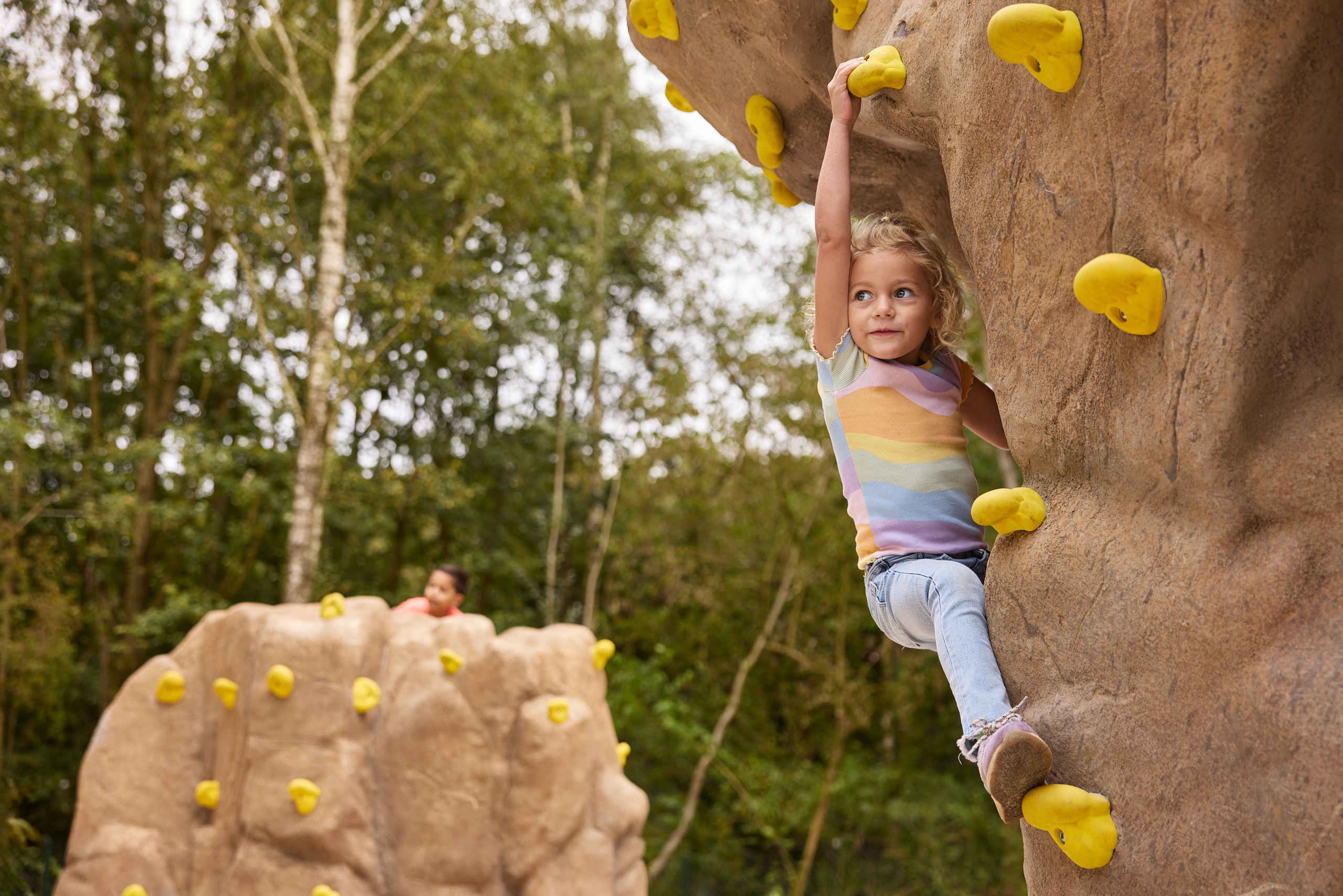 Een meisje klimt op een klimsteen in het boulderpark van Klimrijk Brabant.
