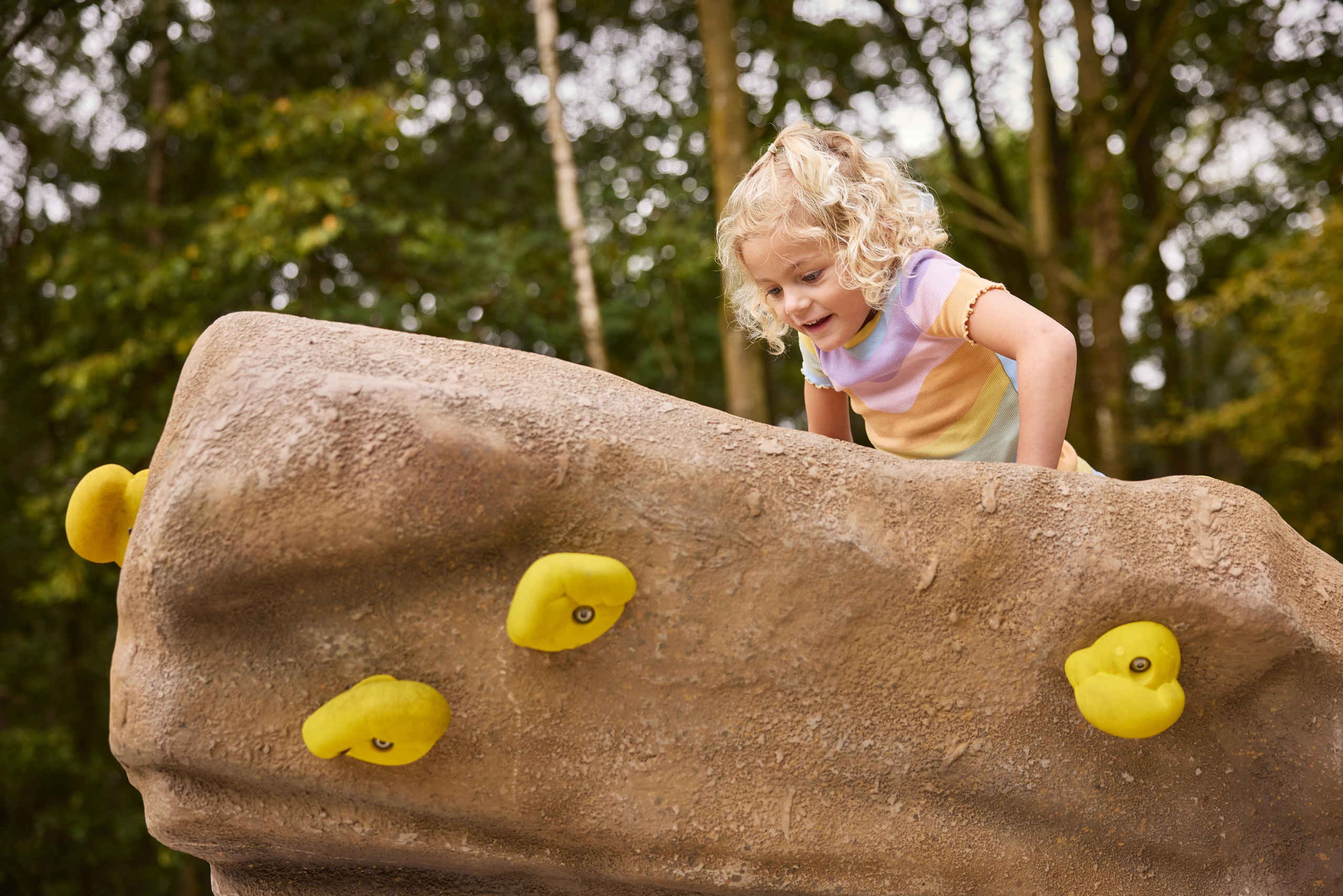 Een meisje klimt op een klimsteen in het boulderpark van Klimrijk Brabant.