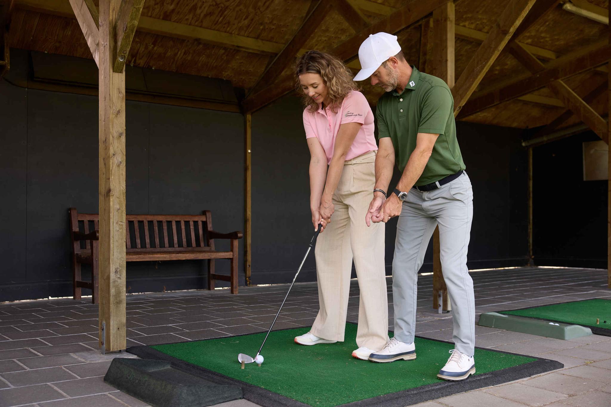 Een vrouw krijgt golfles van de golfpro op de driving range van Golf De Gulbergen