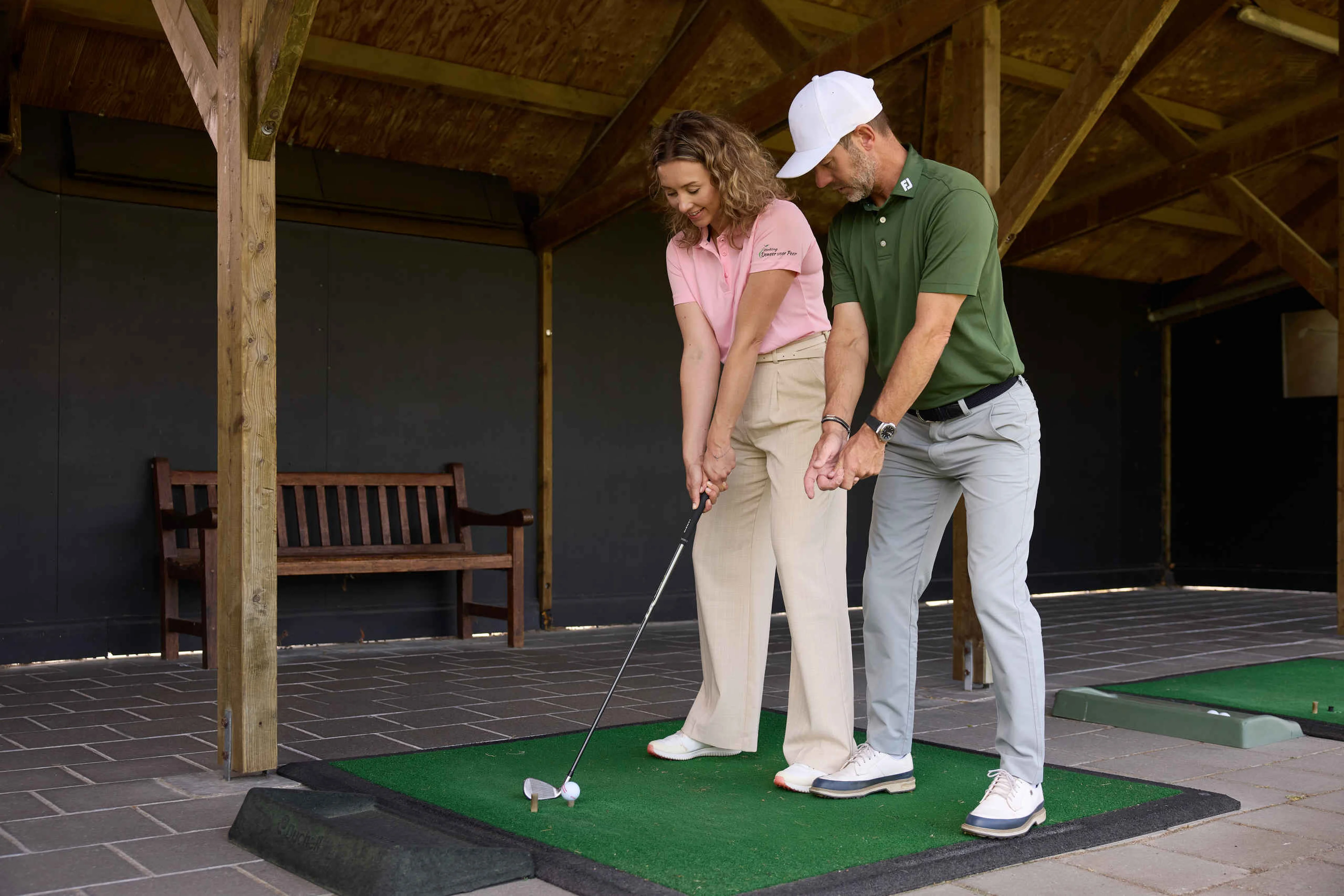 Een vrouw krijgt golfles van de golfpro op de driving range van Golf De Gulbergen