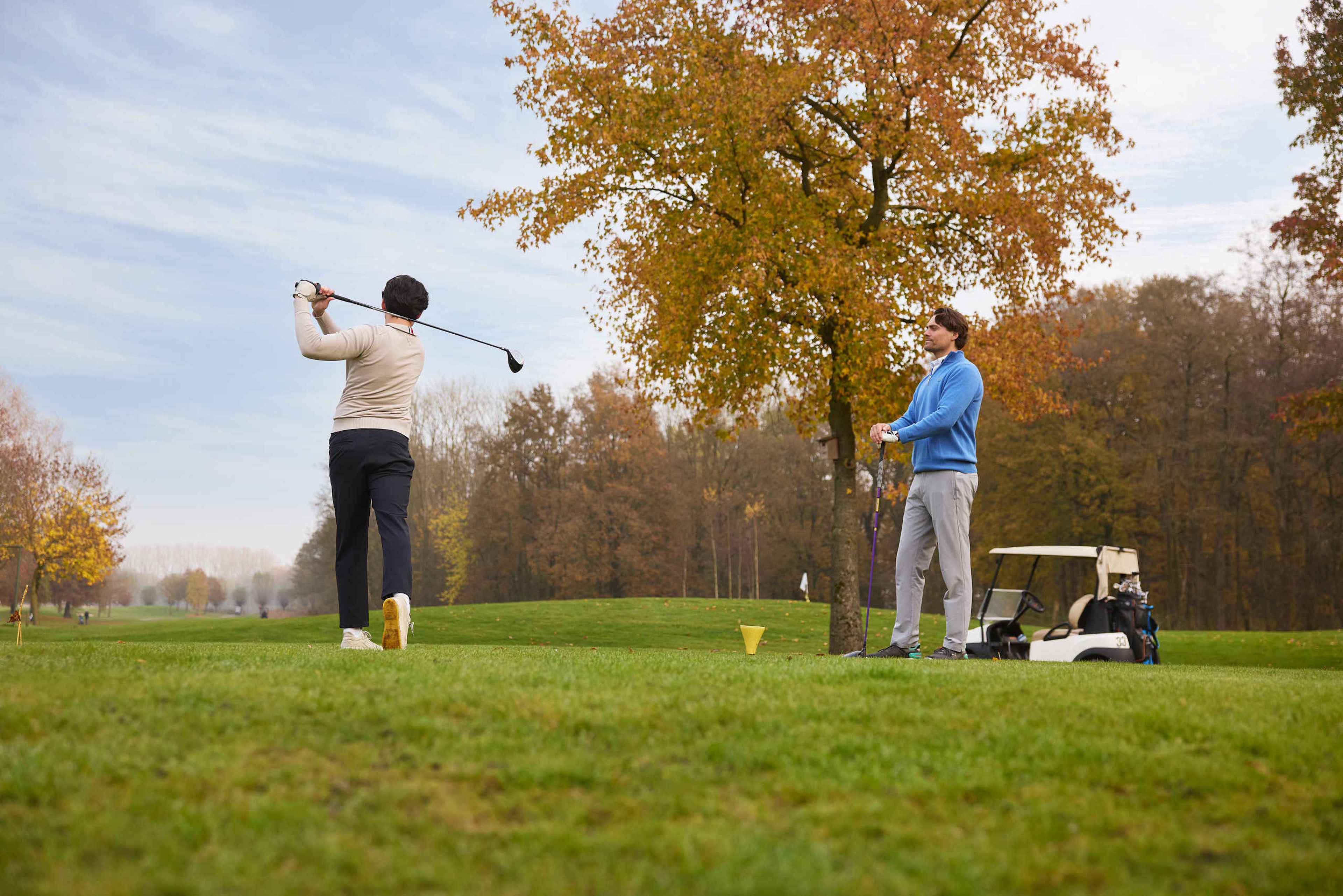 Twee golfers bij de tee van een hole in het najaar op Golf De Gulbergen