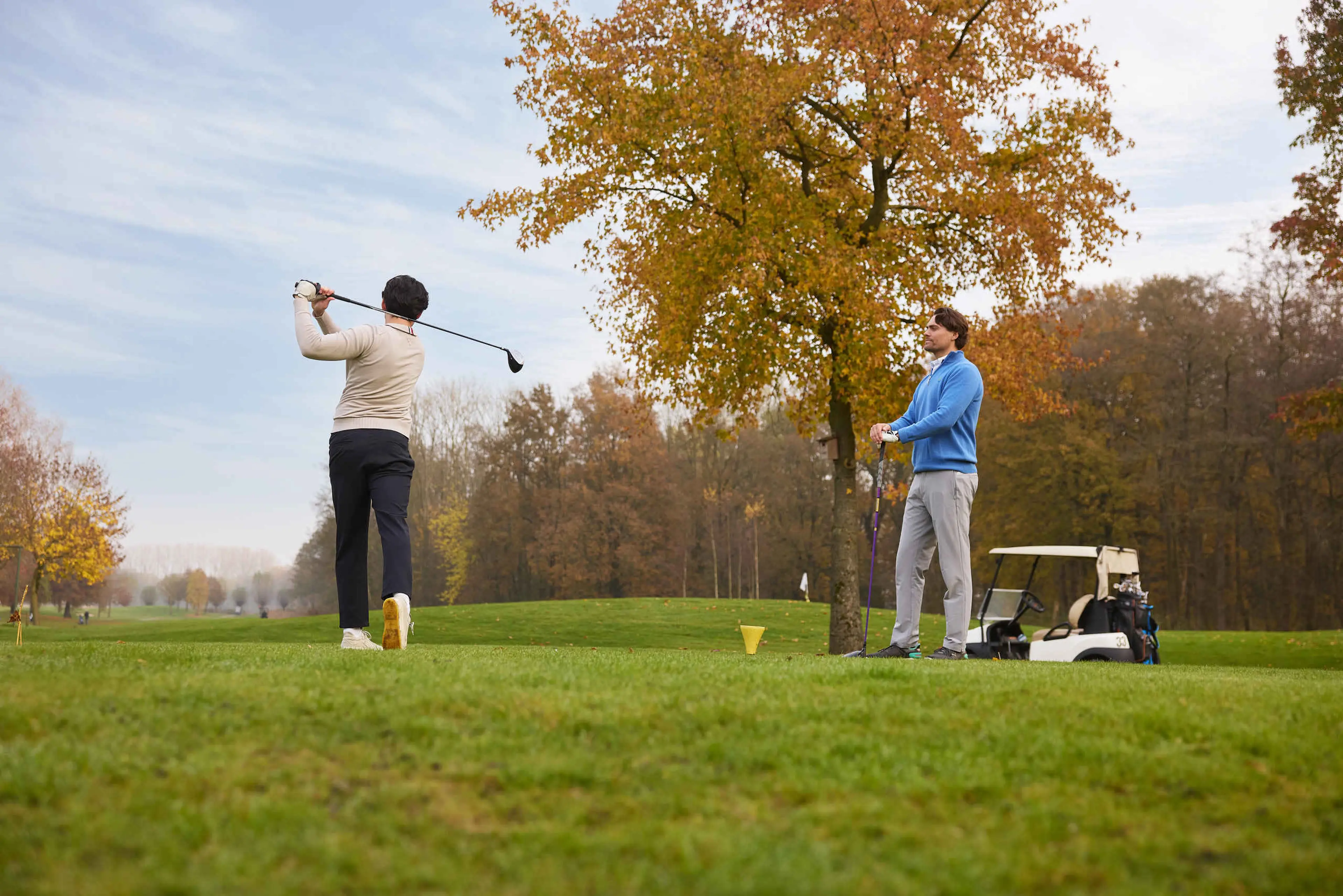 Twee golfers bij de tee van een hole in het najaar op Golf De Gulbergen