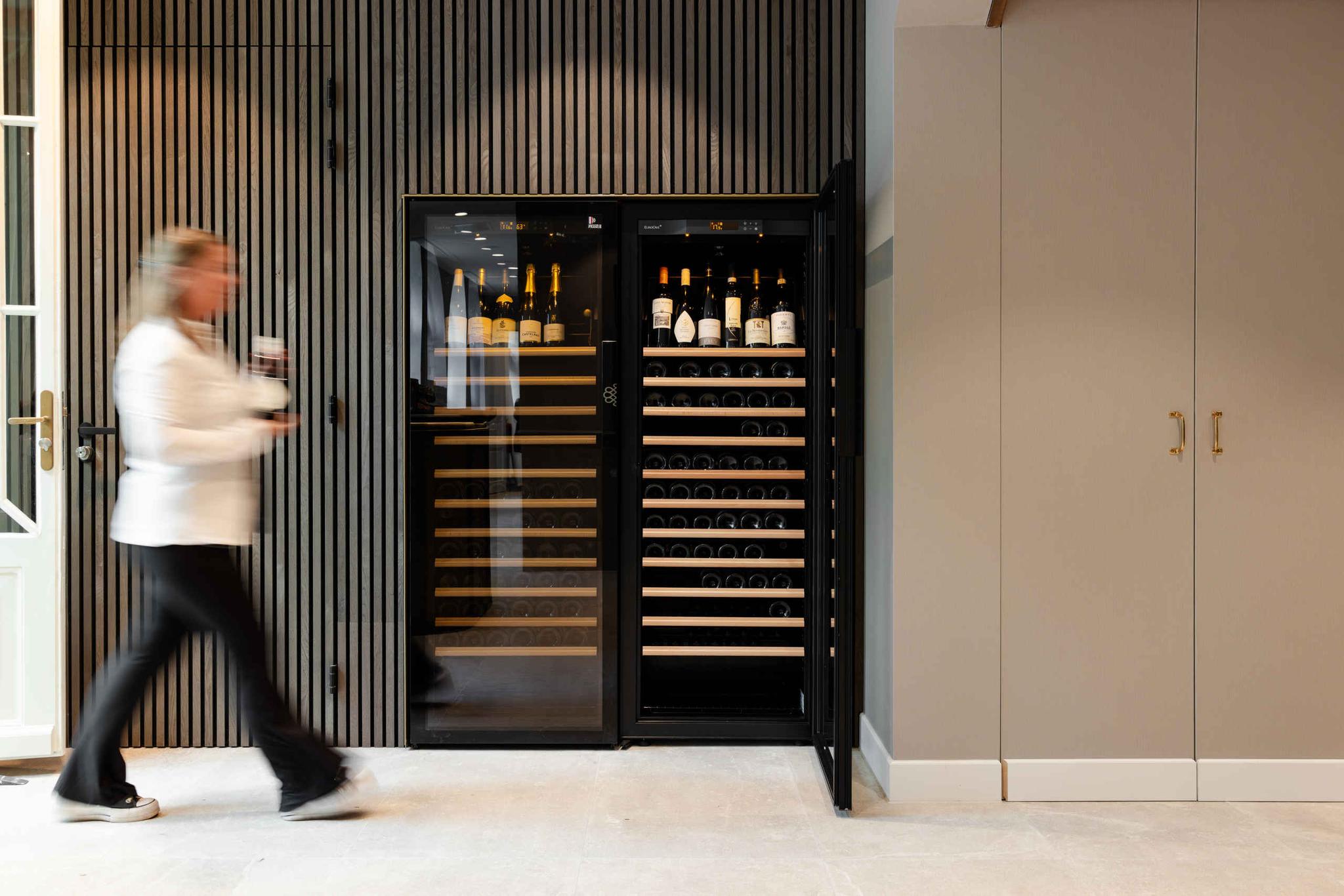 Een serveerster loopt langs de wijnkast bij Orangerie Steenenburg.