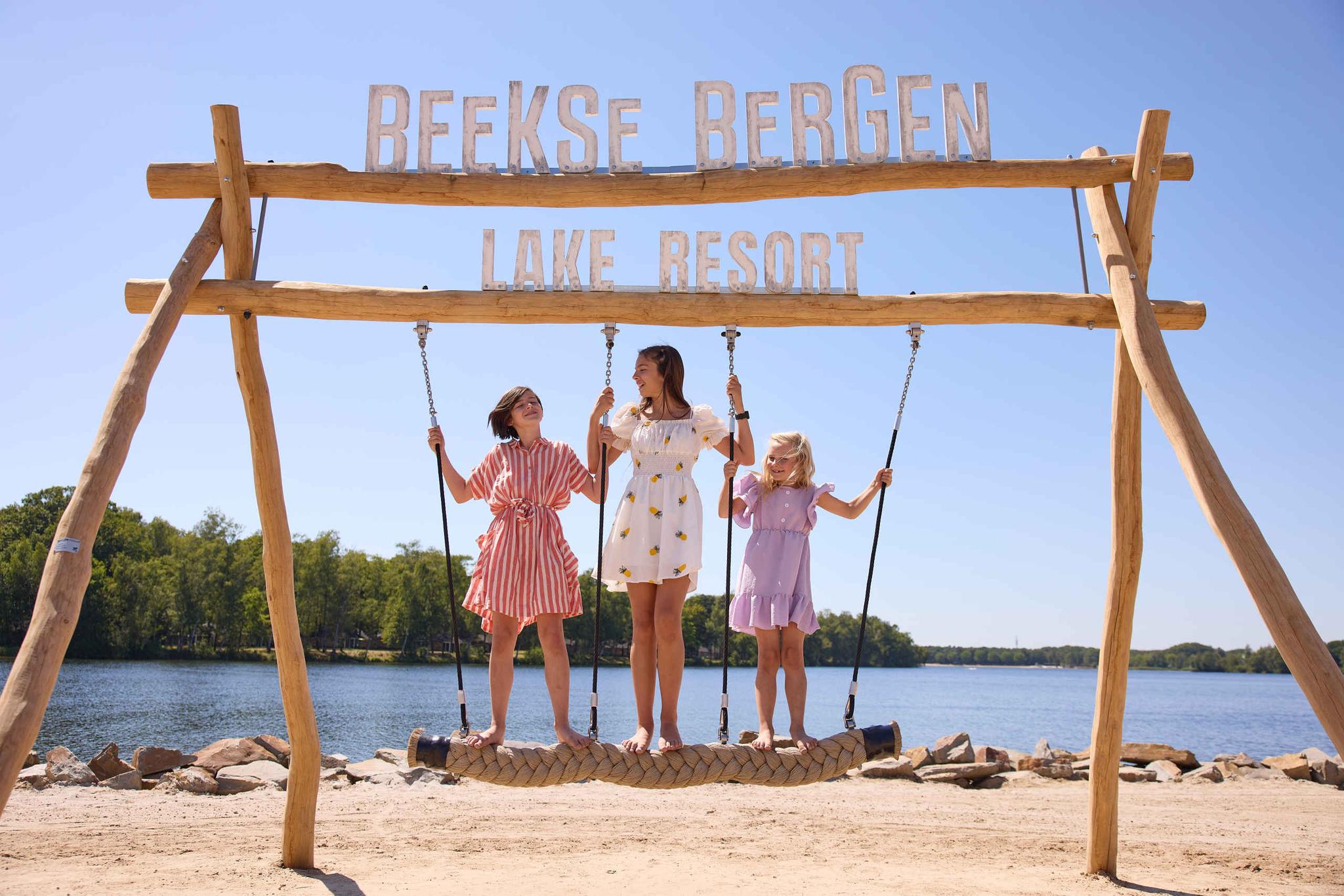 Kinderen op een schommel op het speelstrand bij het Victoriameer bij Lake Resort Beekse Bergen